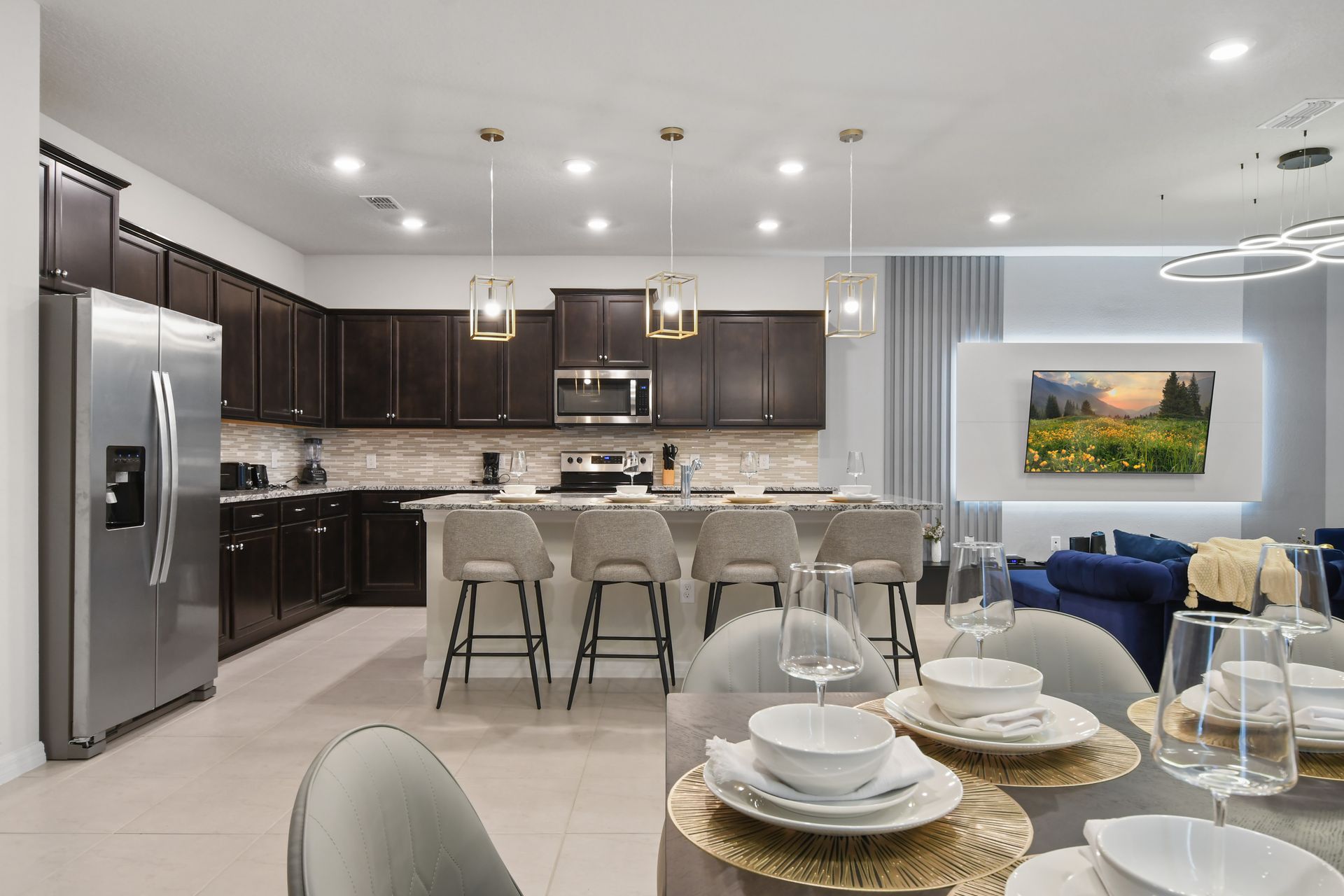 Chef’s kitchen with bar seating, designer lighting, and a cozy living room view.