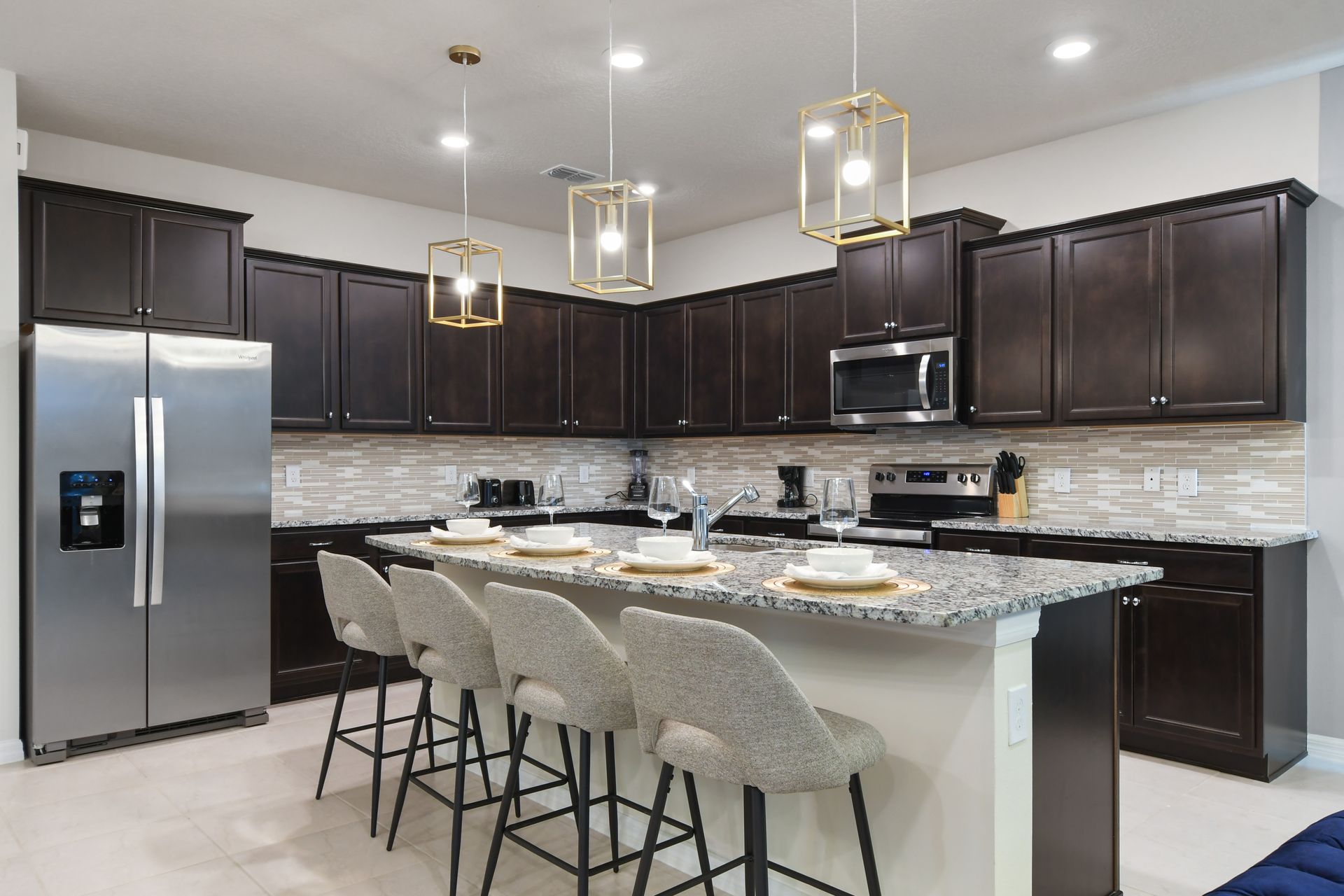 Modern kitchen with granite island, bar seating, and elegant pendant lighting.