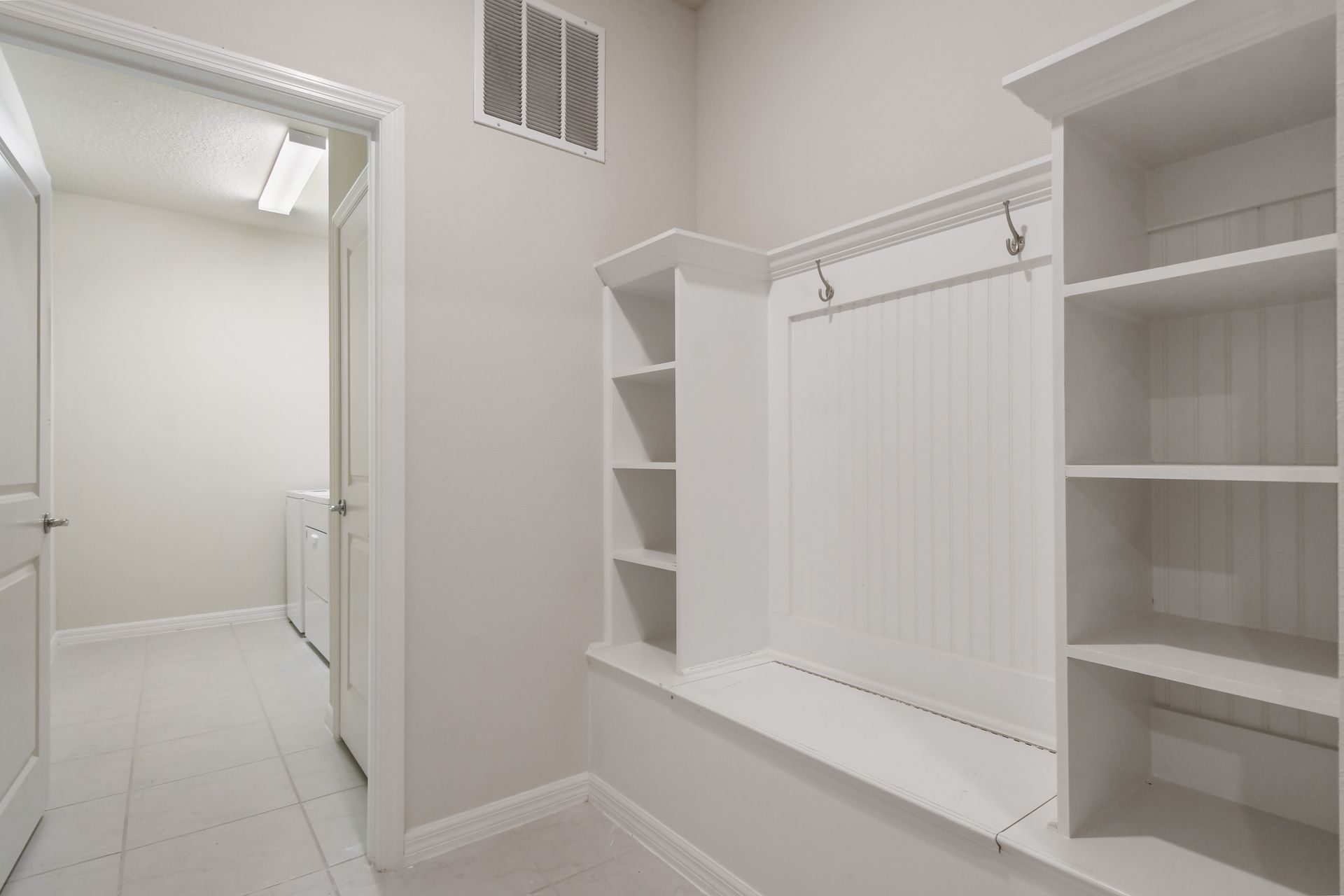 Spacious mudroom with built-in bench, cubbies, and direct laundry access.