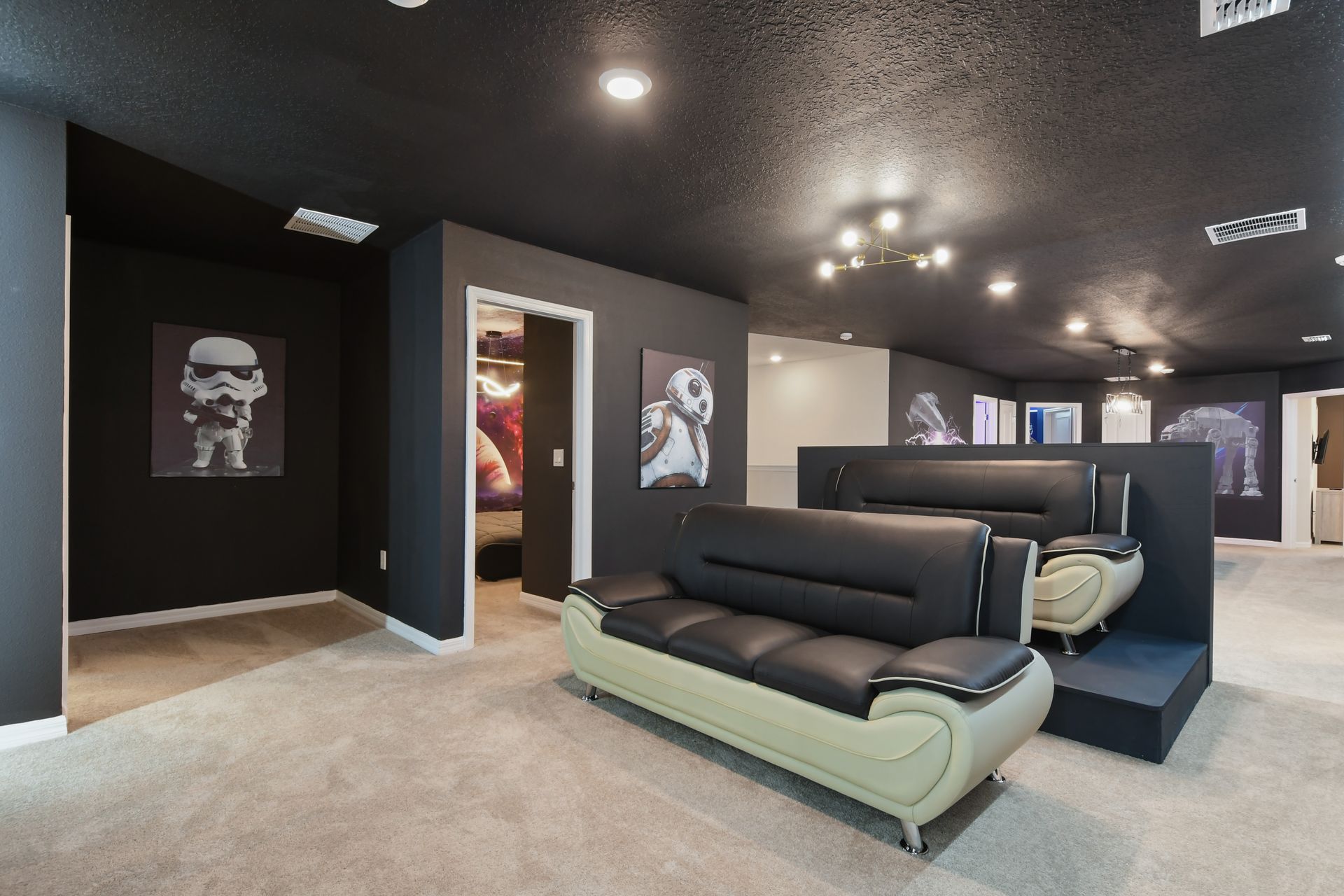 Spacious home theater lounge with Star Wars art, tiered seating, and cozy vibes.