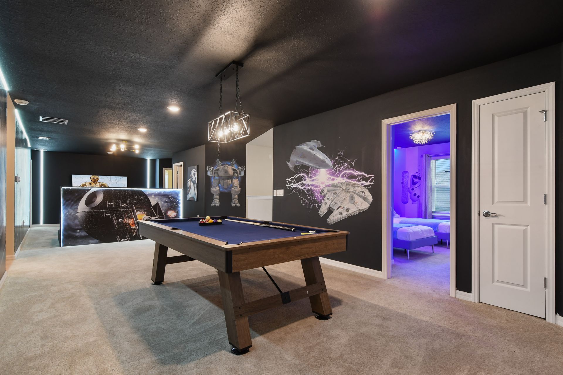 Galaxy-inspired game loft with pool table, Star Wars art, and themed room access.