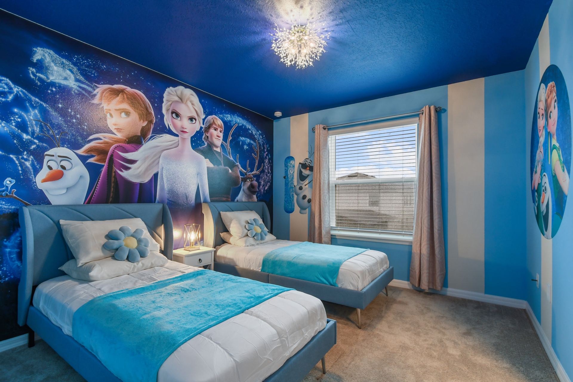 Frozen-themed bedroom with twin beds, vibrant wall art, and magical icy blue décor.