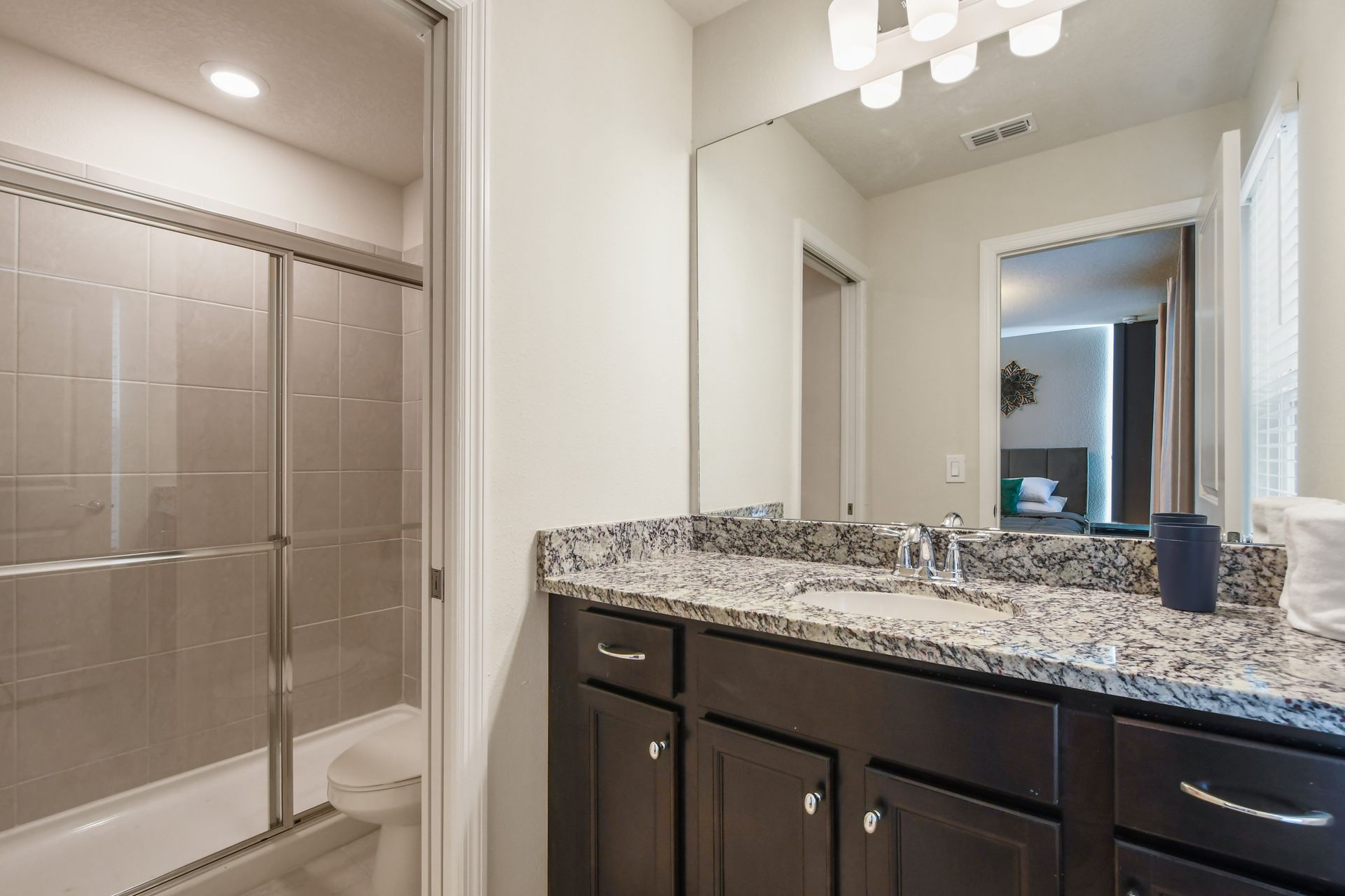 Modern bathroom with granite vanity, walk-in shower, and direct bedroom access.