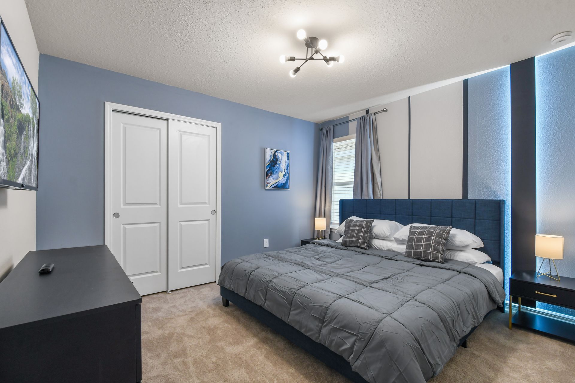 Sleek blue-accented bedroom with a king bed, modern lighting, and stylish decor.