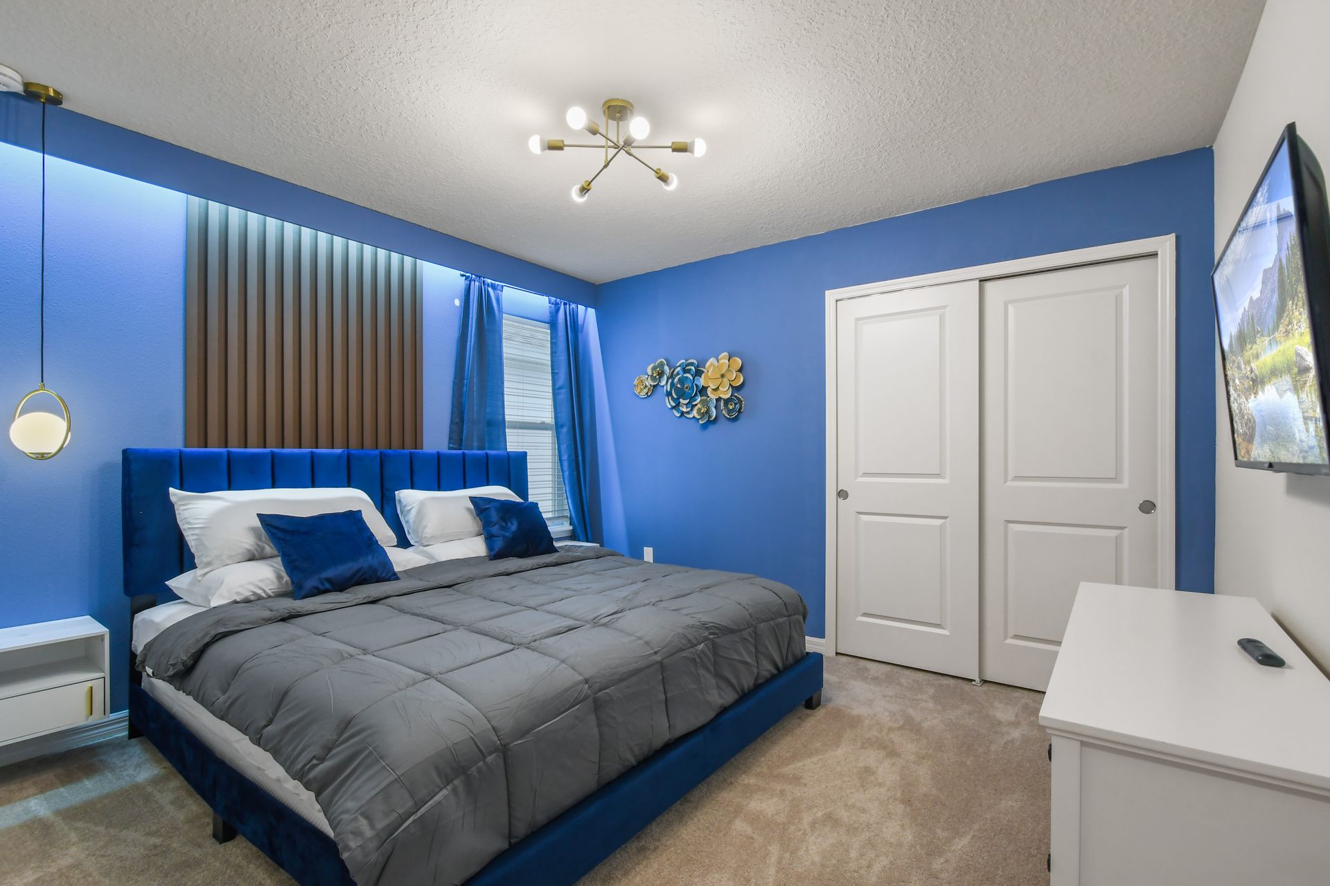 Vibrant blue bedroom with a king bed, glowing accent wall, and modern flair.