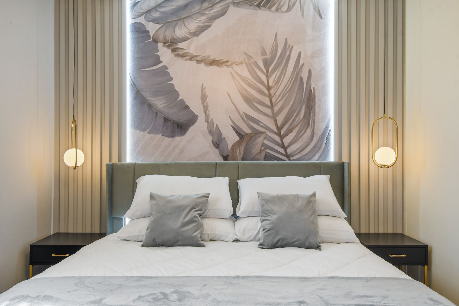 Elegant king bed with layered pillows, modern lighting, and nature-inspired art.