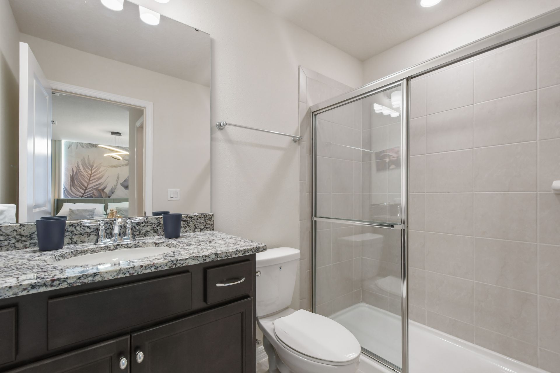 Stylish ensuite bath with granite counters and sleek walk-in glass shower.