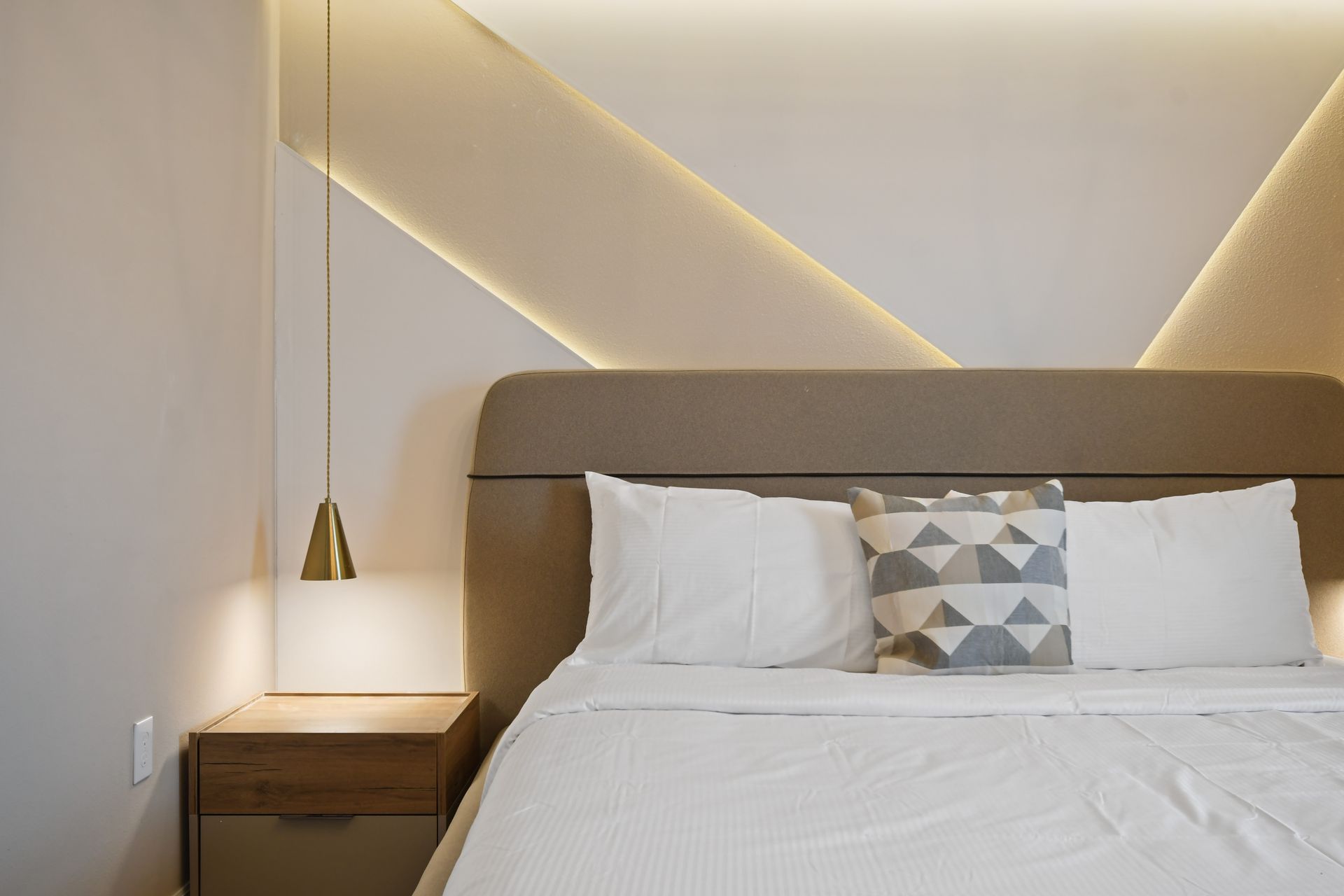 Modern bedroom with ambient lighting, plush bedding, and elegant gold accents.