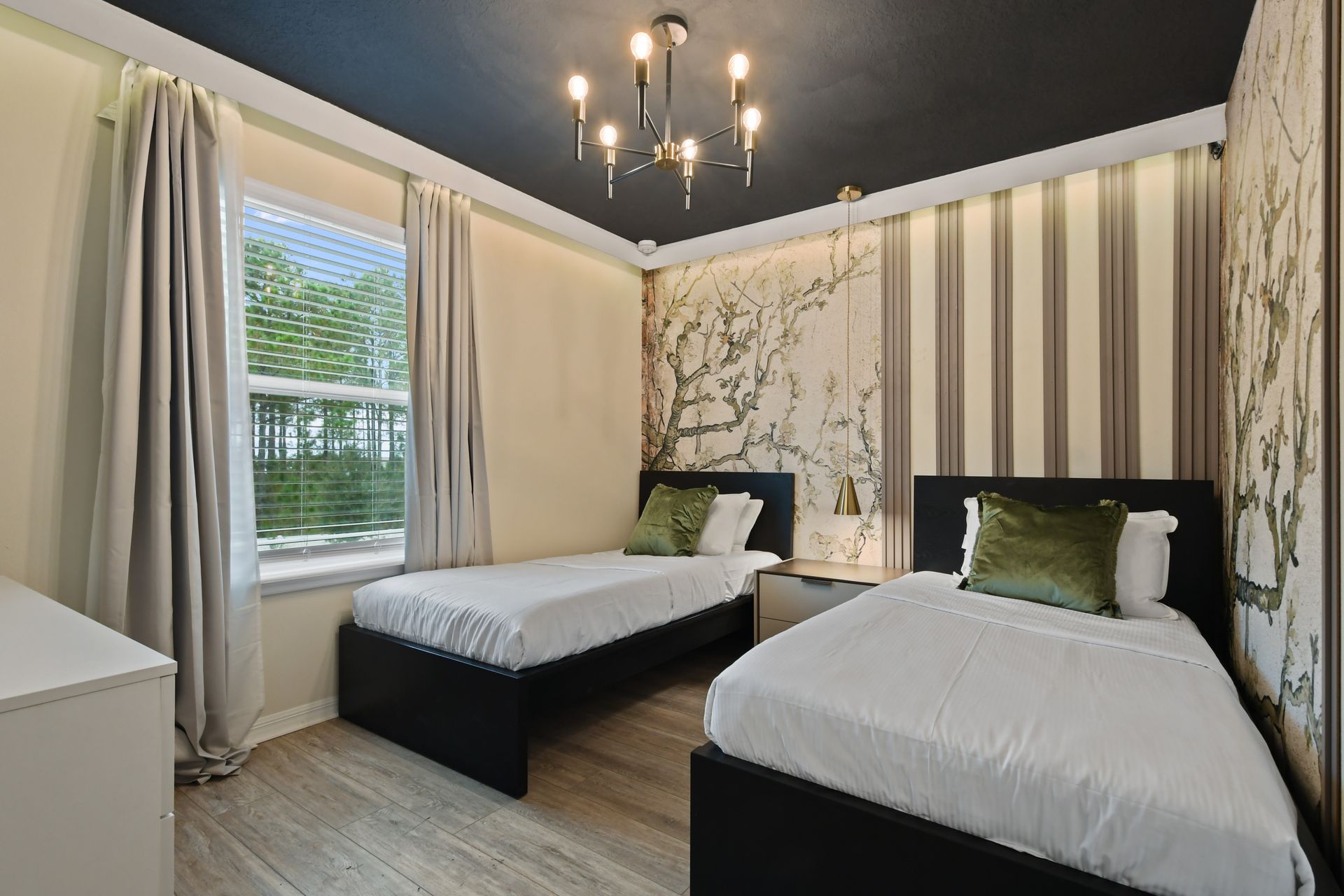 Elegant twin room with nature-inspired accent wall, modern chandelier, and cozy beds
