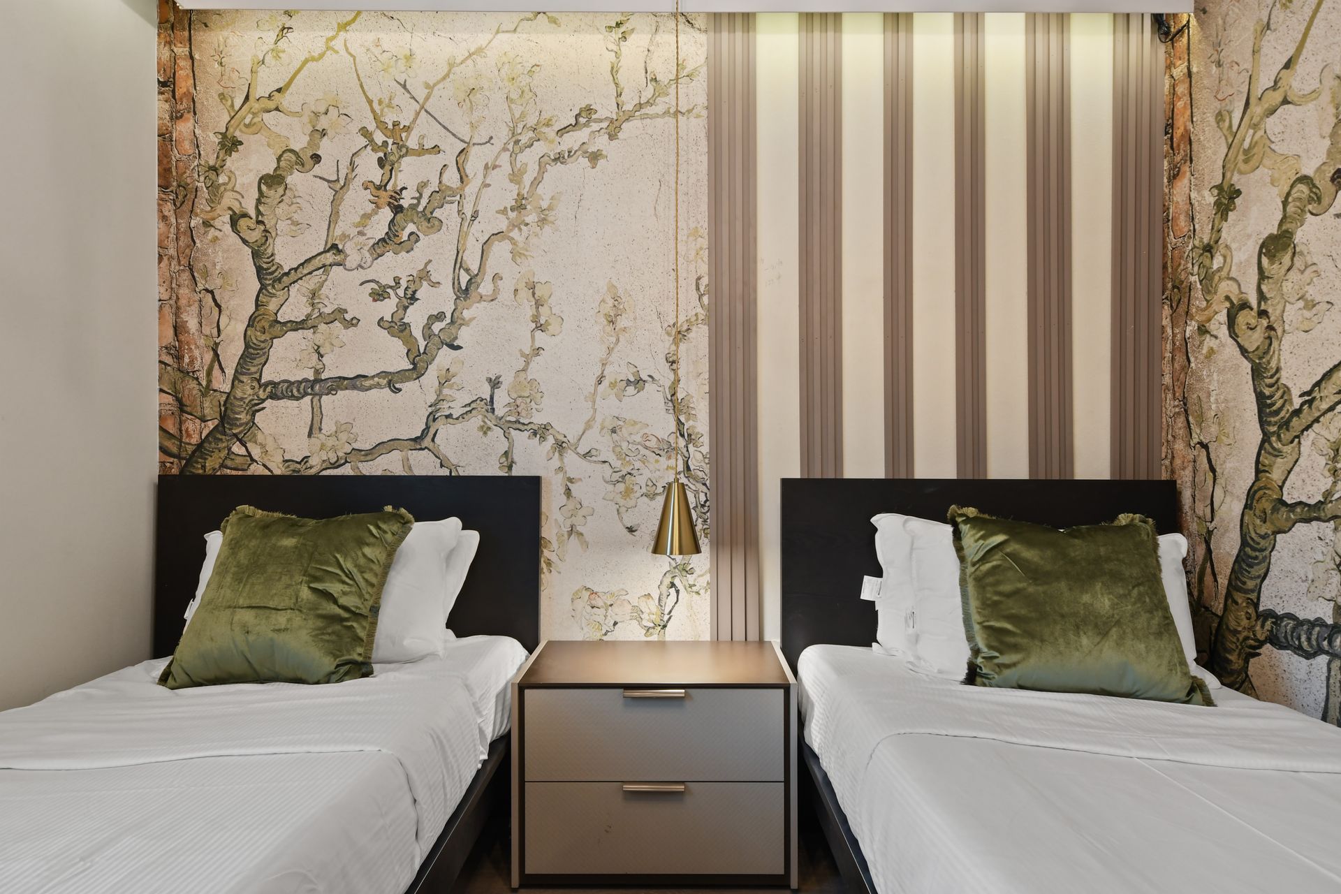 Elegant twin room with nature-inspired accent wall, modern chandelier, and cozy beds
