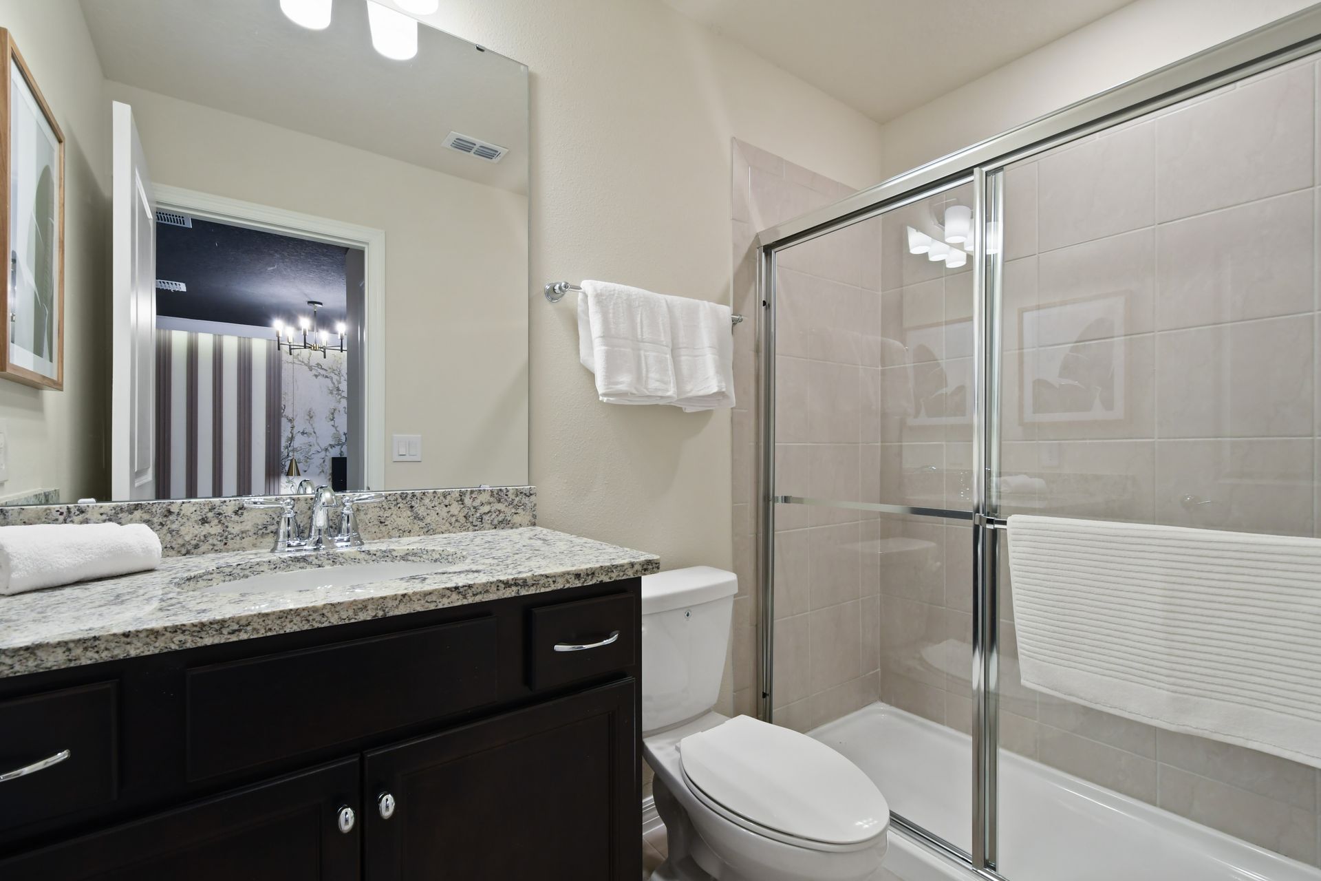 Stylish bathroom with granite vanity, glass shower, plush towels, and chic design
