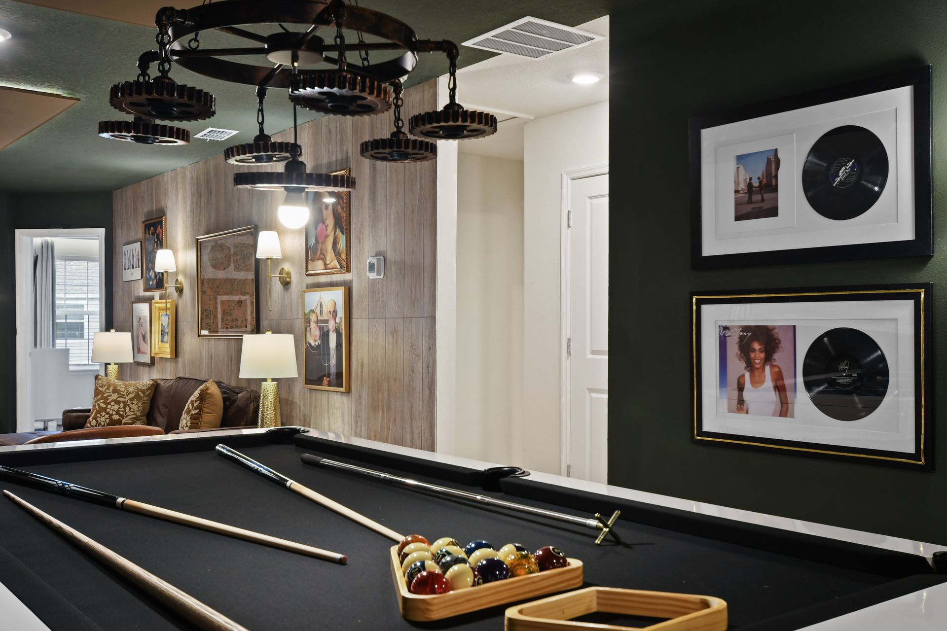 Chic game room with modern pool table, record wall art, cozy lounge and bar
