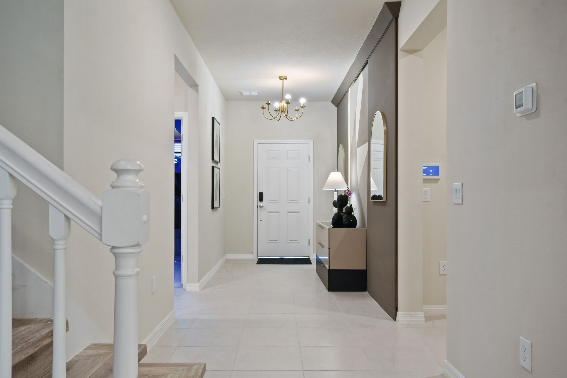 Bright modern entryway with geometric wall, chic chandelier, stylish mirror, and decor
