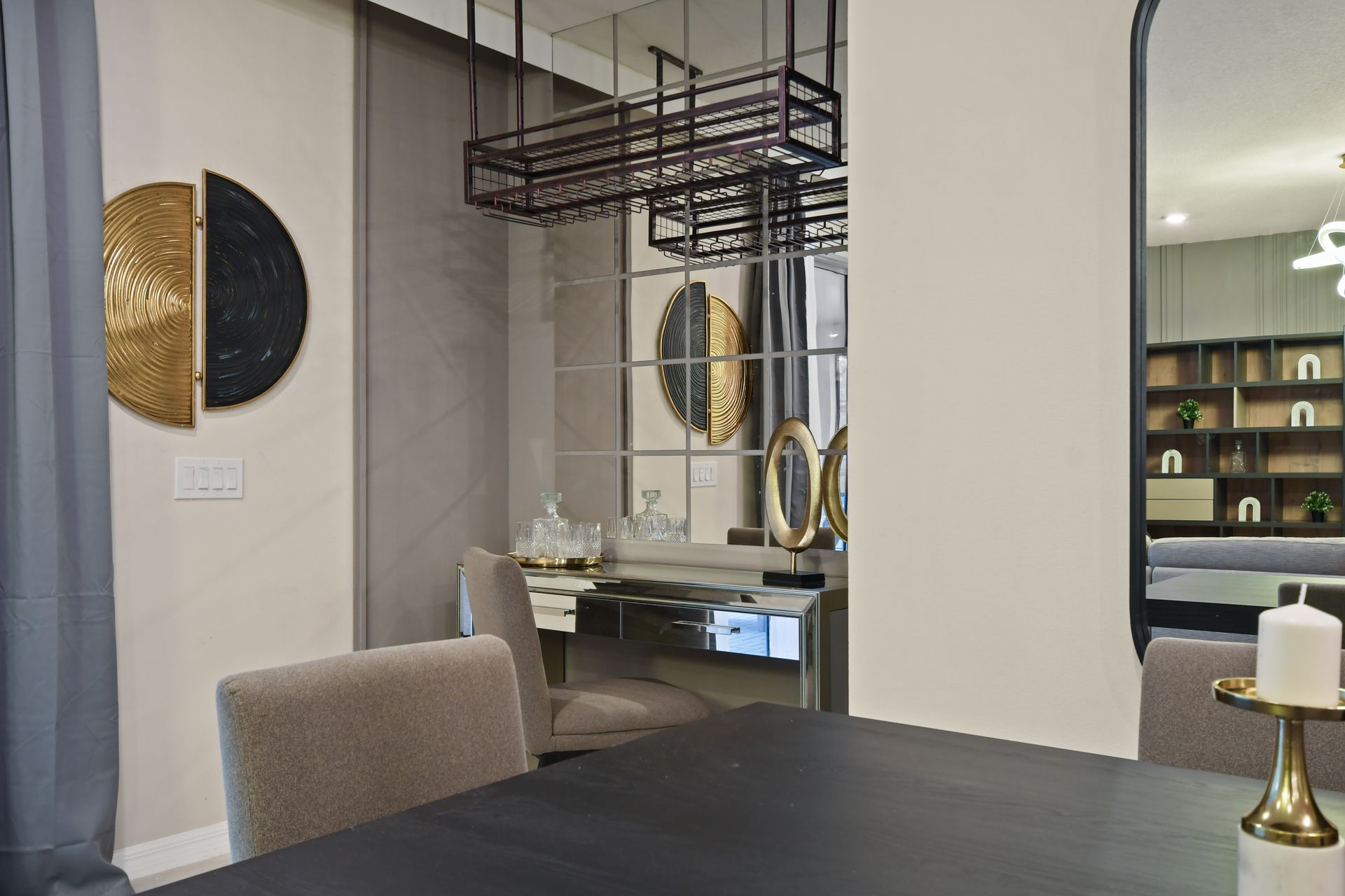 Elegant dining nook with mirrored bar, sculptural decor, gold accents, and cozy seating
