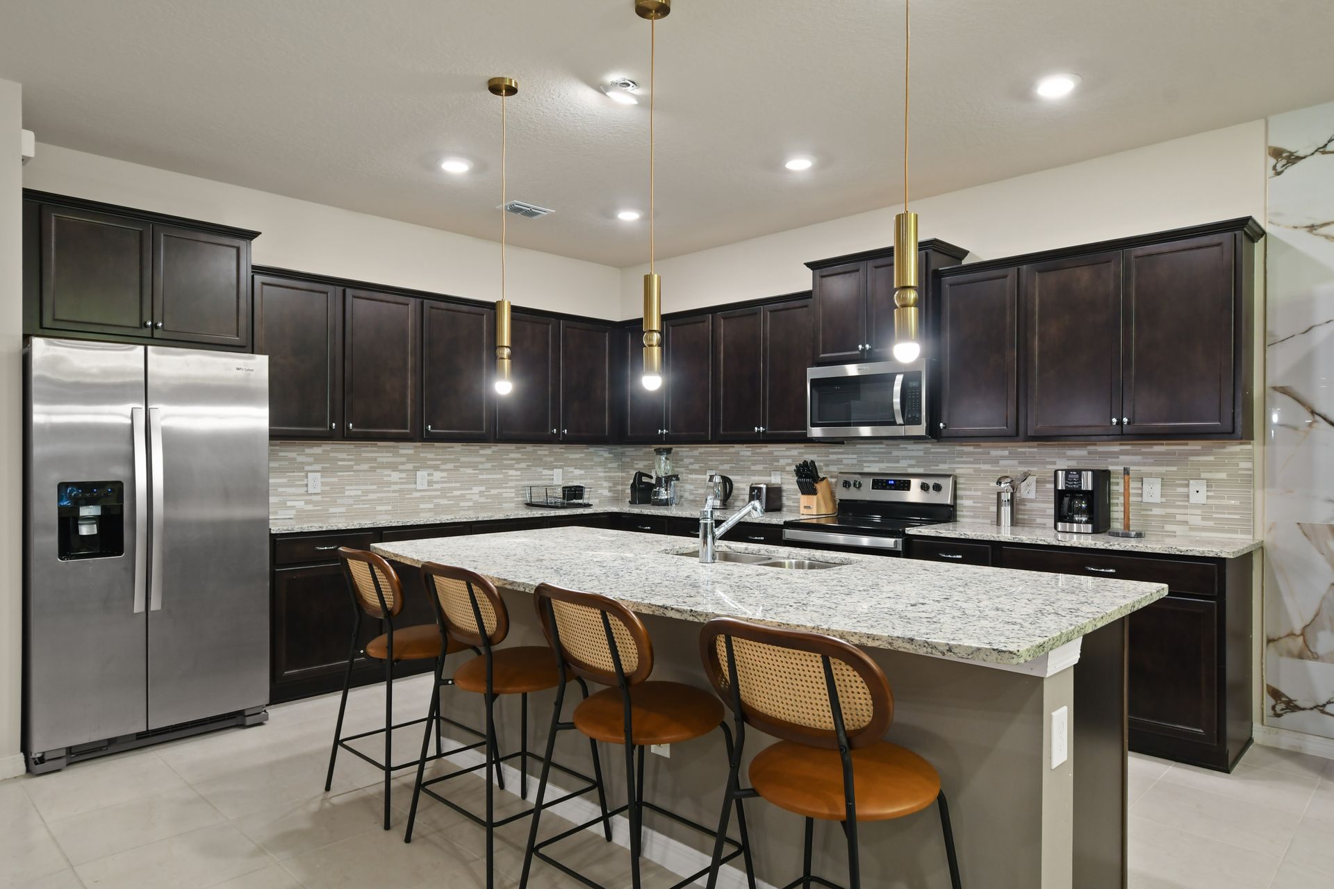 Open-concept kitchen and living area with modern lighting and ample seating.