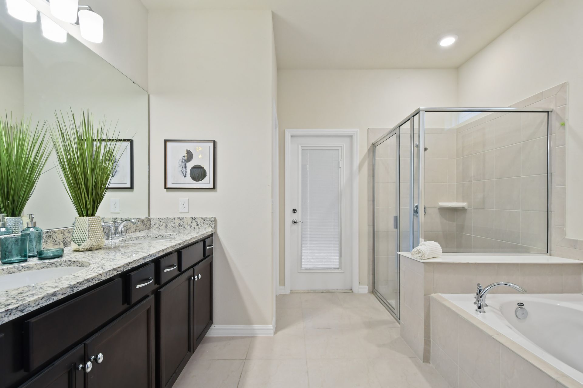 Spa-like bathroom with double vanity, glass shower, soaking tub, and elegant decor
