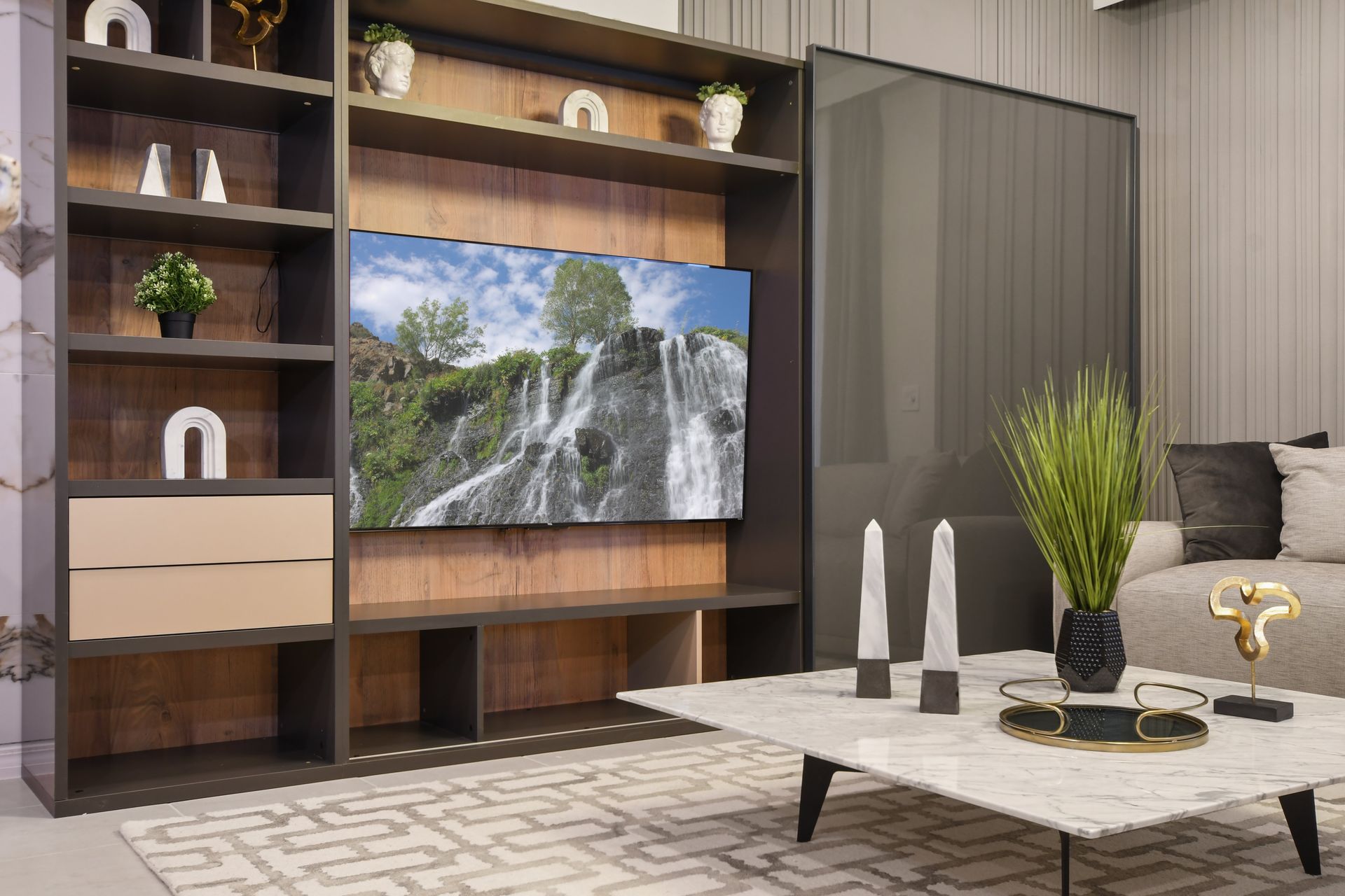 Modern living area with built-in TV wall, stylish shelves, marble coffee table, and chic decorative accents
