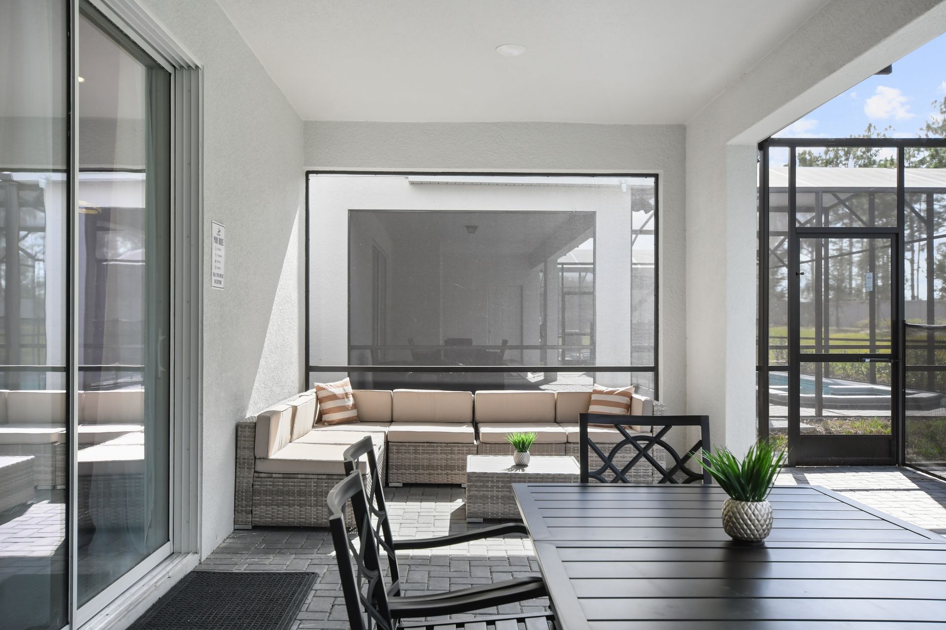 Cozy screened patio with cushioned sectional, dining table, and sunny pool access
