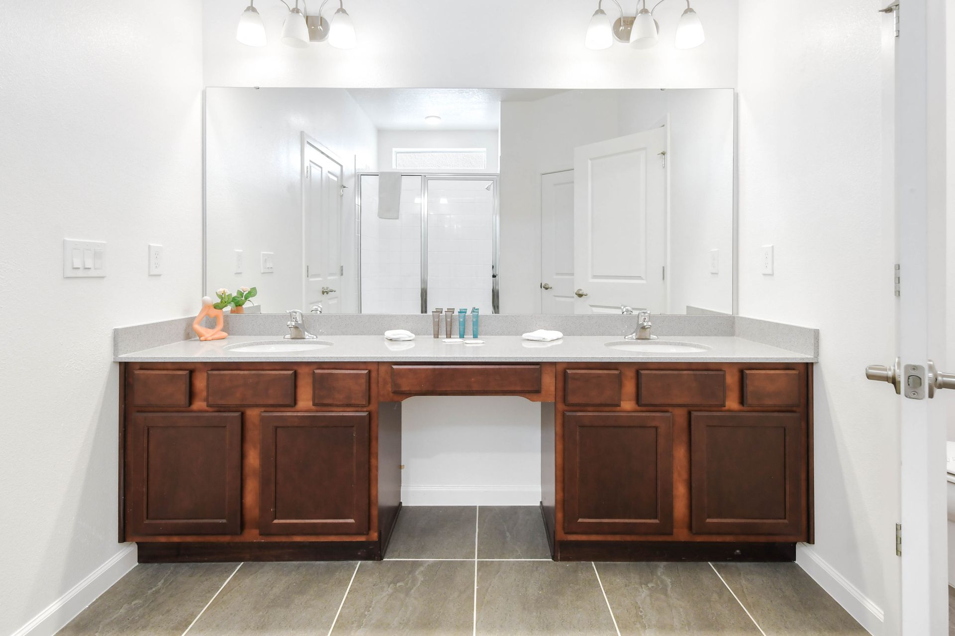 Bright, modern bathroom with dual sinks, large mirror, and walk-in shower.