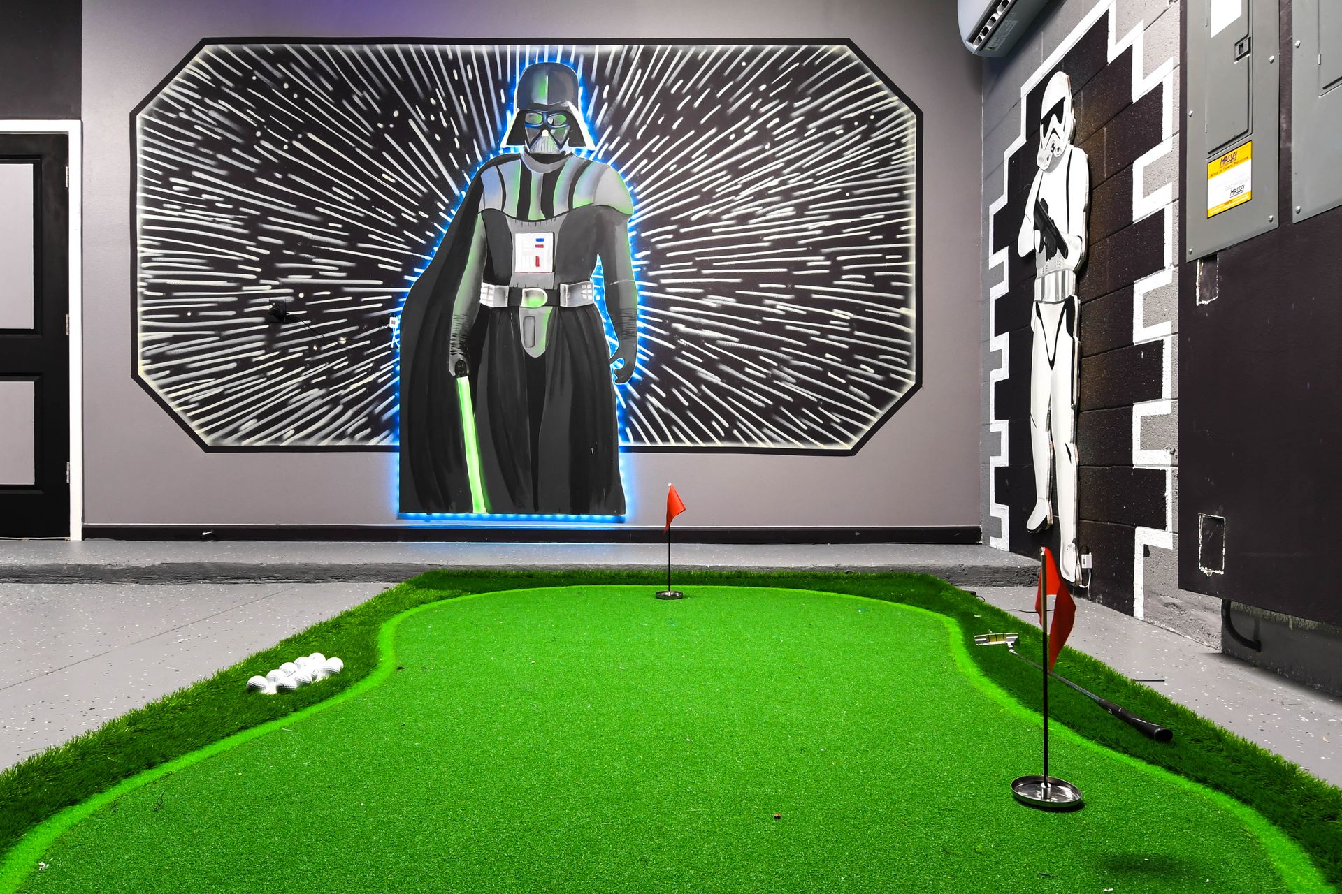 Mini putting green with galactic murals and glowing lights for space-age fun.
