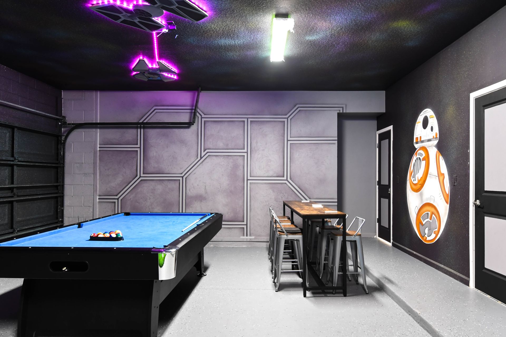 Futuristic game room with pool table, sci-fi walls, and BB-8 mural accent.