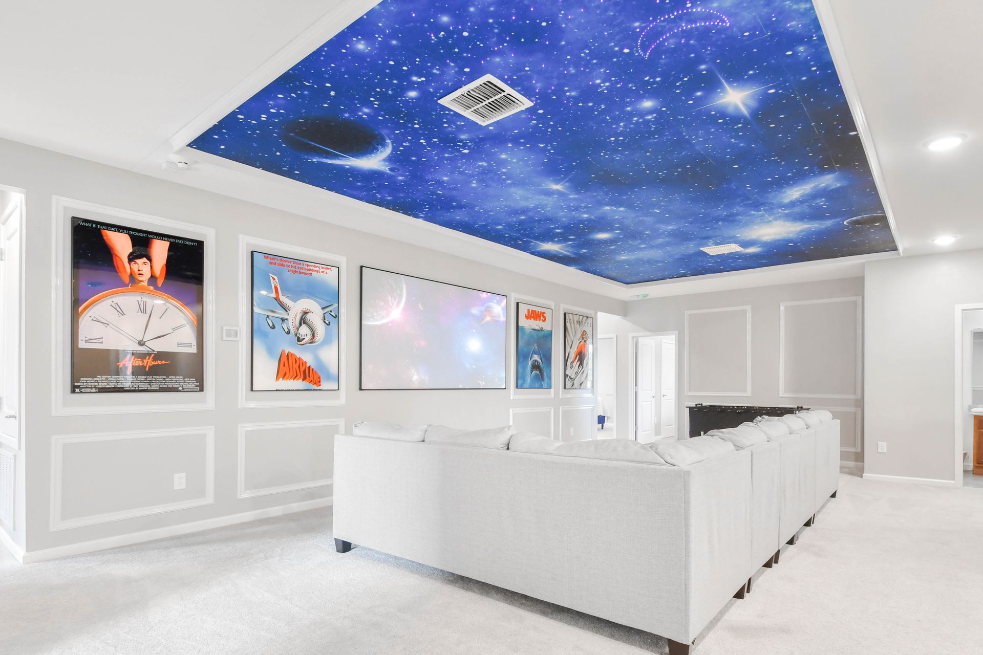 Stunning home theater with space-themed ceiling, classic posters, and plush seating.