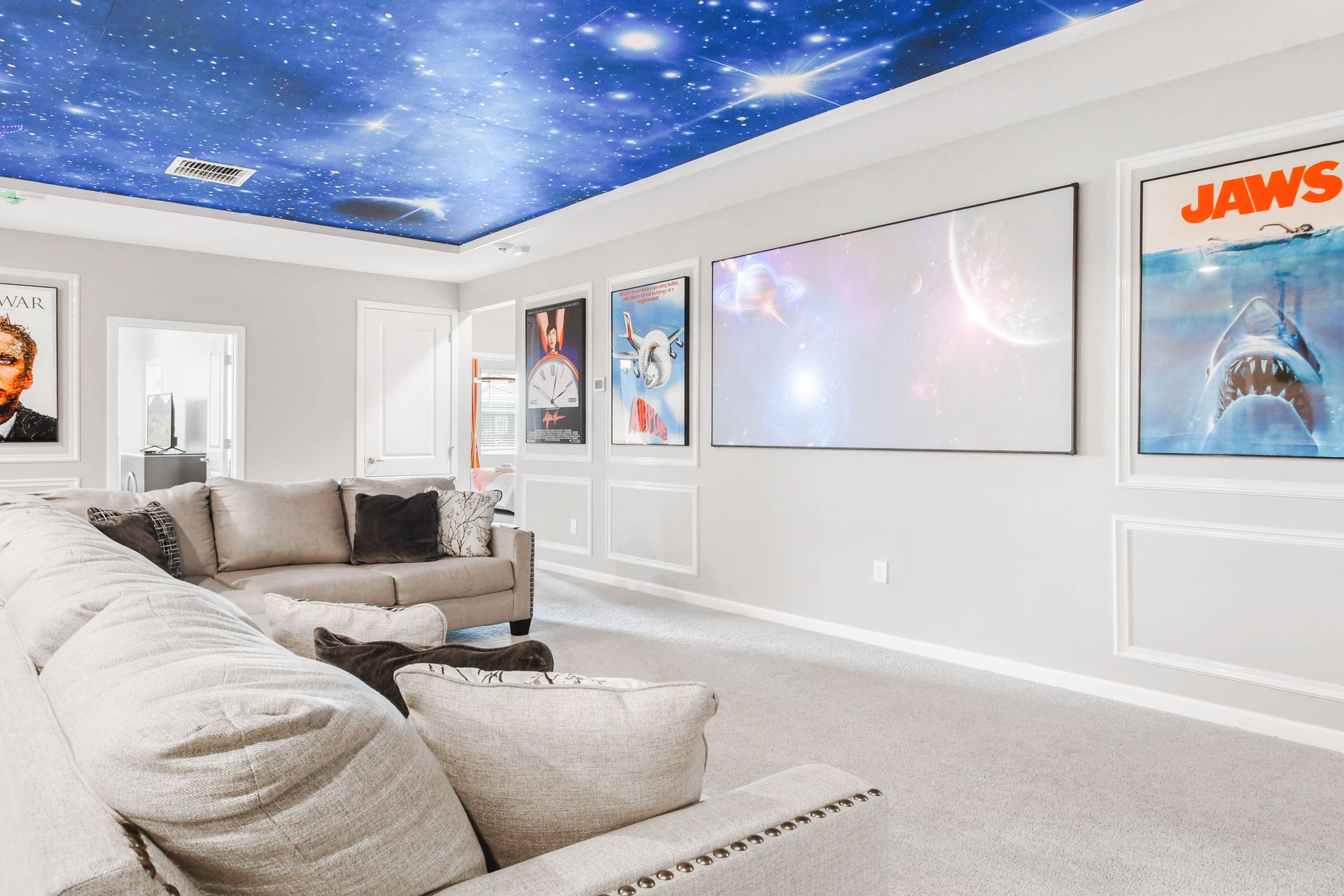 Cozy movie lounge with galaxy ceiling, large screen, and iconic film posters.