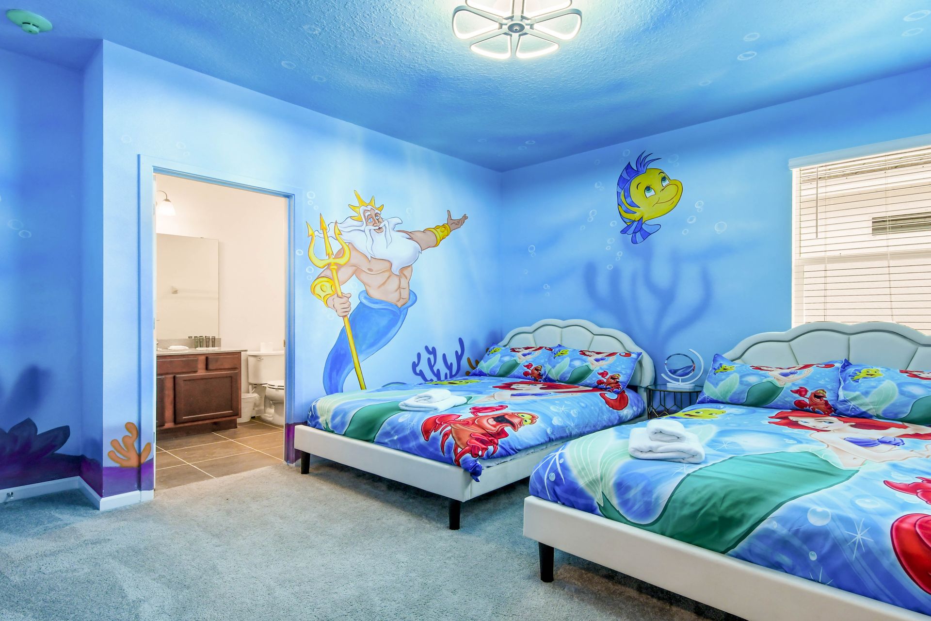 Underwater-themed kids’ room with twin beds, murals, and private bathroom.
