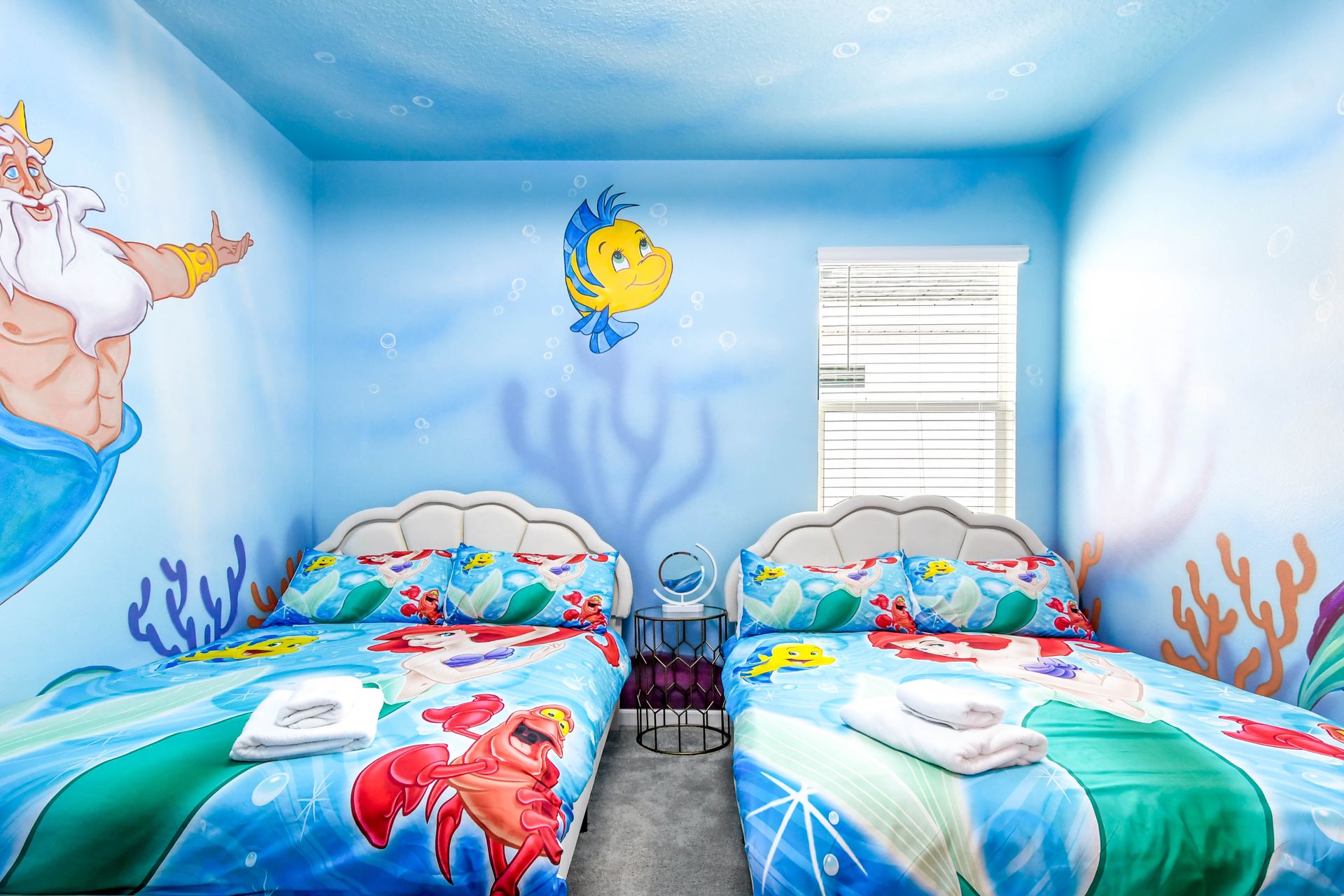 Magical Little Mermaid room with twin beds, ocean murals, and vibrant bedding.