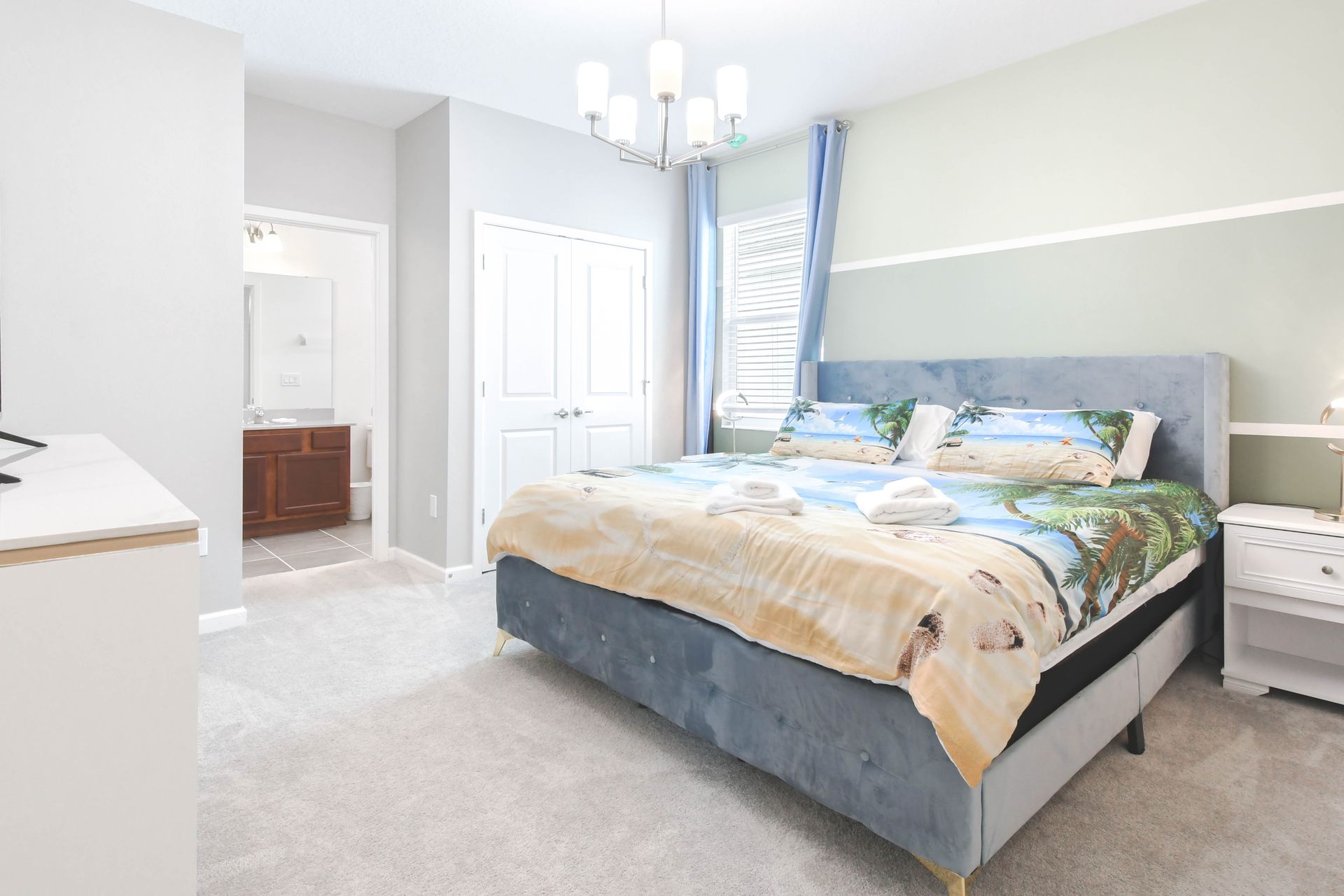 Cozy king bedroom with tropical bedding, soft carpet, and attached bathroom.