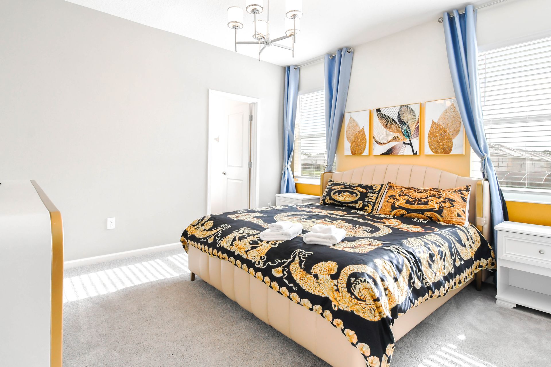 Stylish king bedroom with gold accents, elegant bedding, and bright natural light.