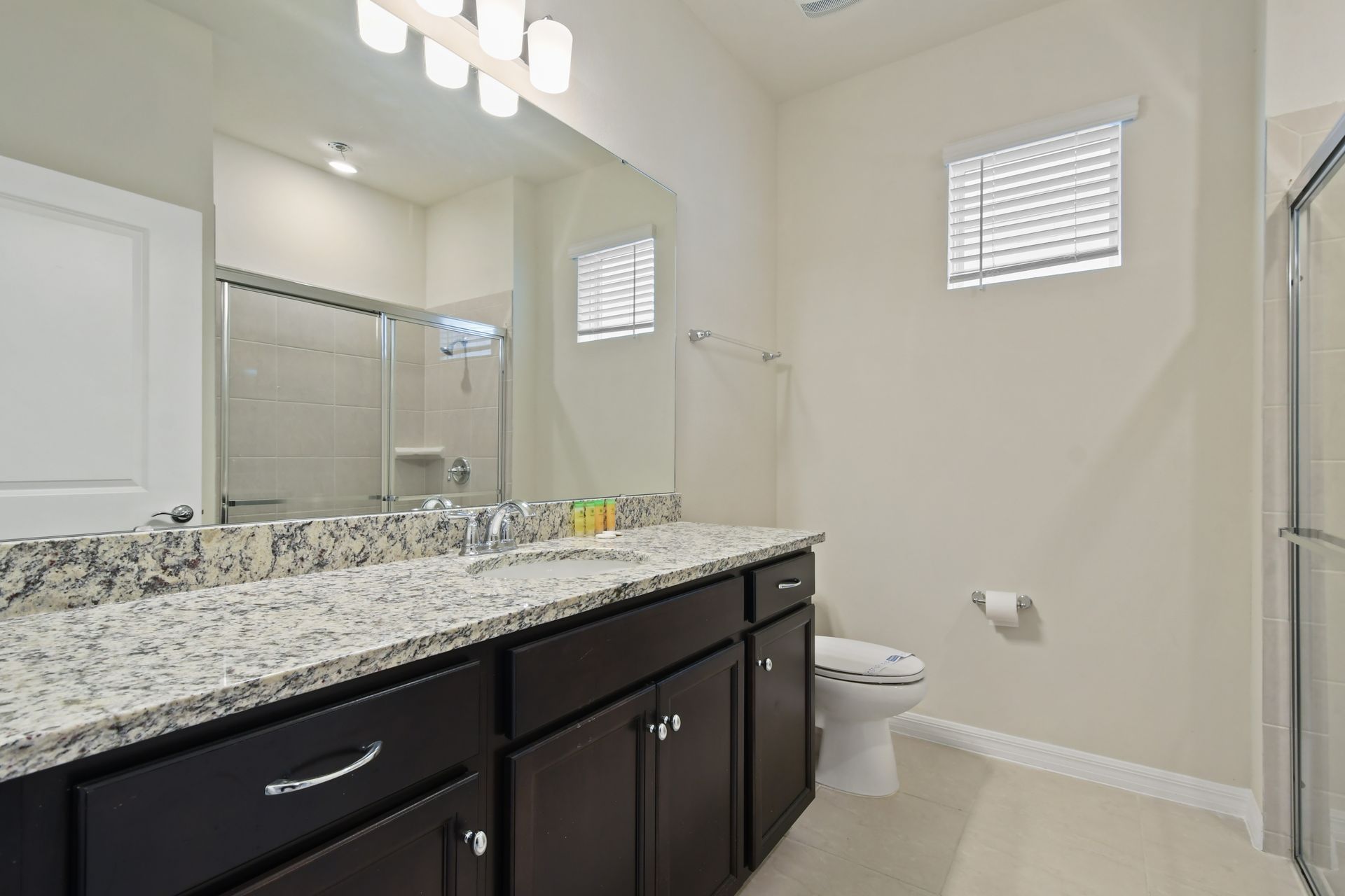 Elegant bathroom with granite countertops, dual sinks, and a walk-in glass shower.
