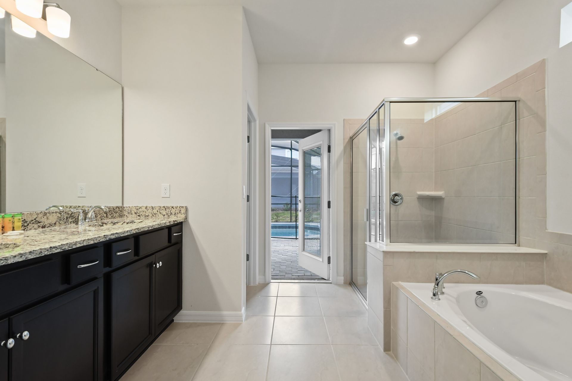 Spacious ensuite with double vanity, soaking tub, and direct poolside access.
