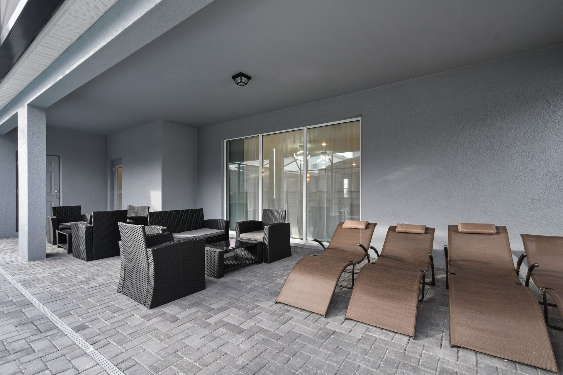 Covered patio with stylish loungers and cozy seating, perfect for outdoor relaxation.
