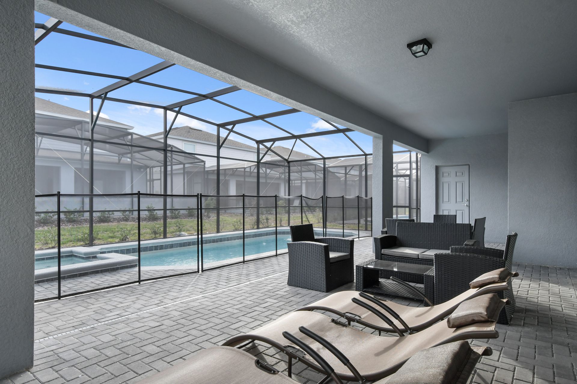 Covered lanai with lounge seating, poolside views, and a screened-in oasis.
