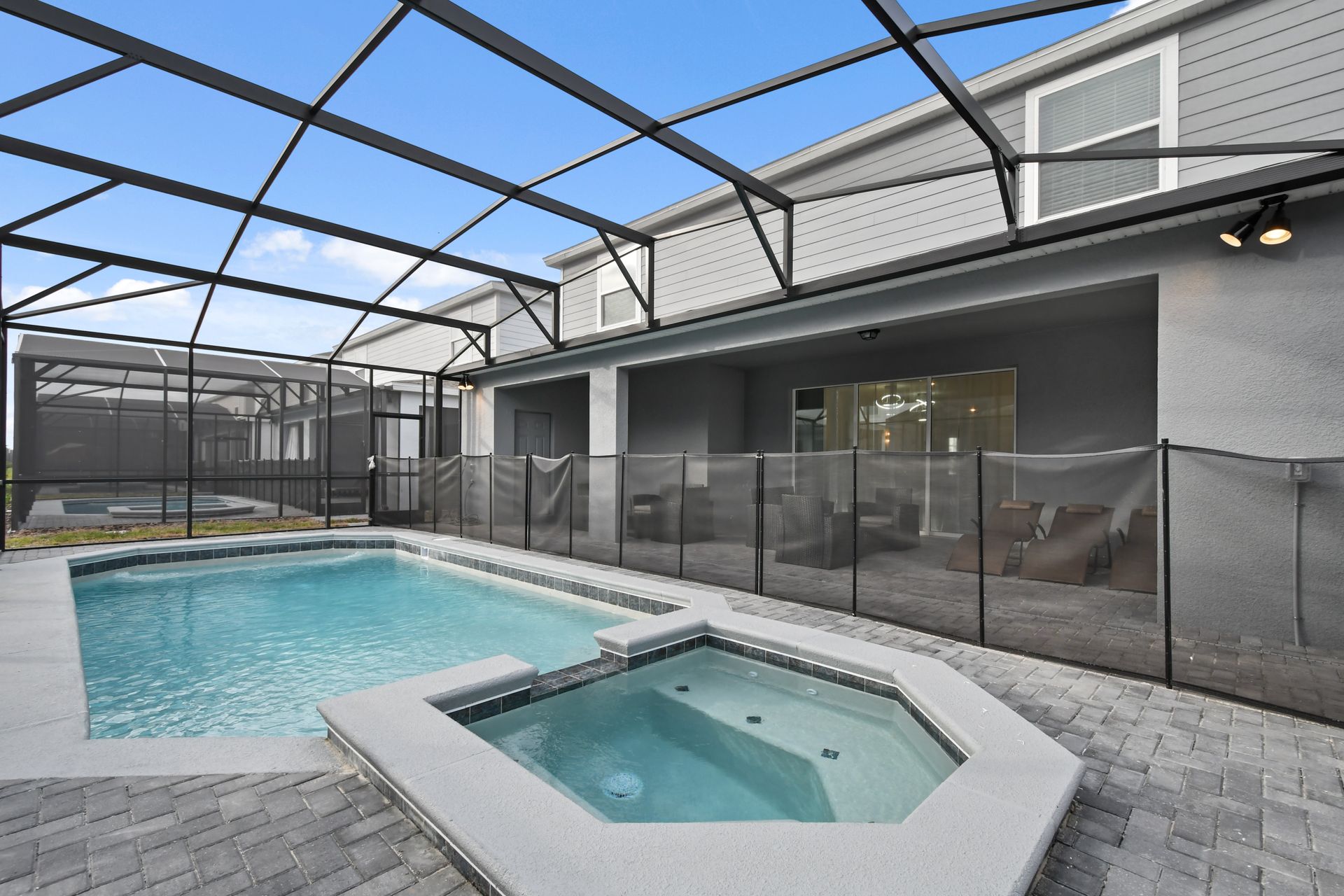 Private screened-in pool and spa with lounge seating and a spacious patio area.
