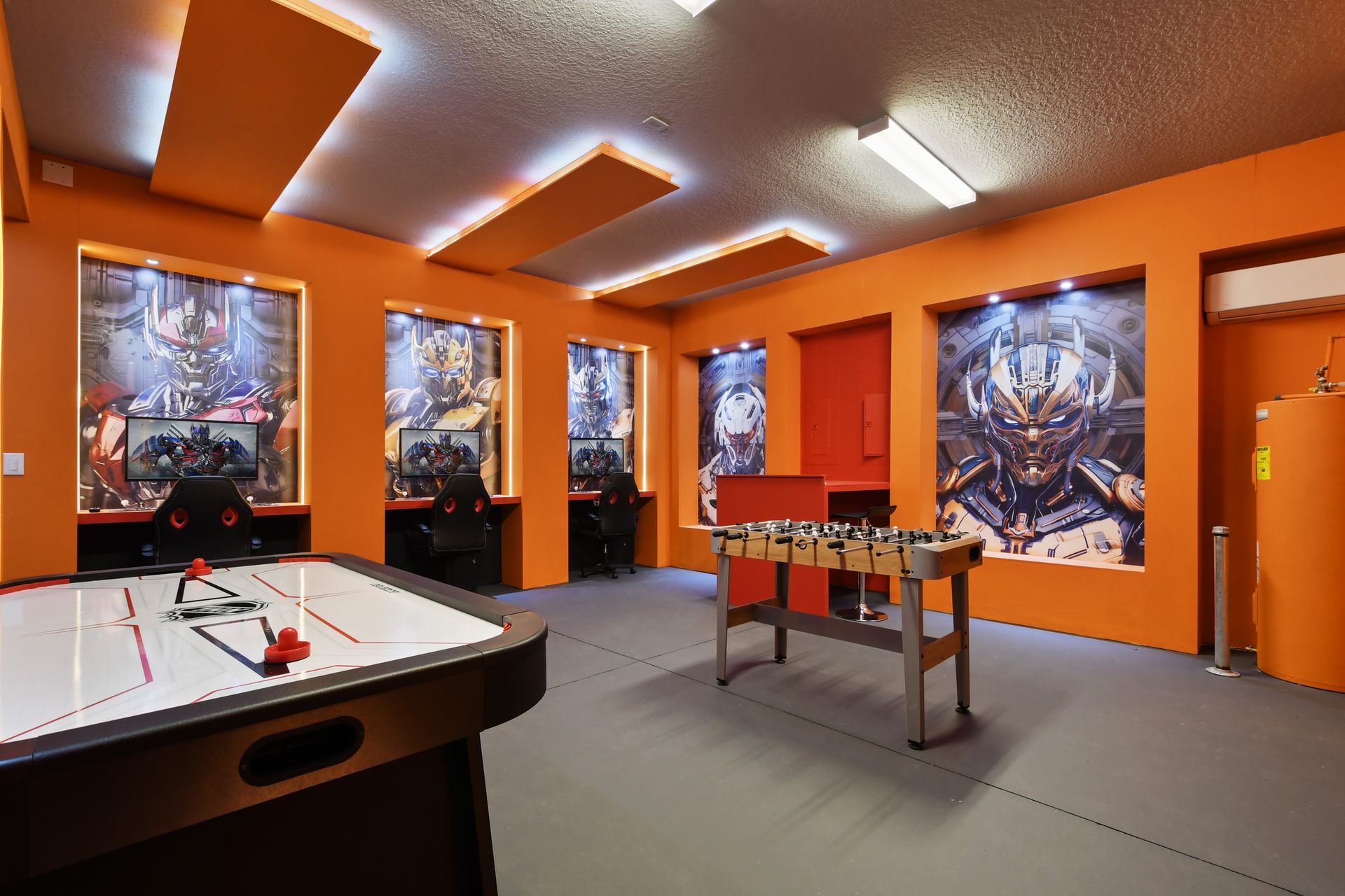 Futuristic game room with PCs, foosball, air hockey, and bold sci-fi decor.
