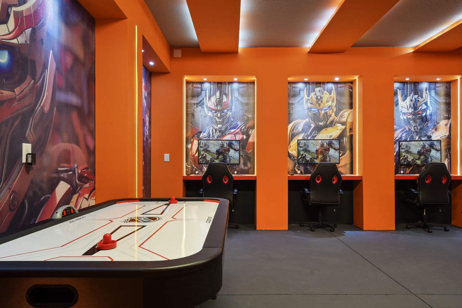 Futuristic game room with PCs, foosball, air hockey, and bold sci-fi decor.
