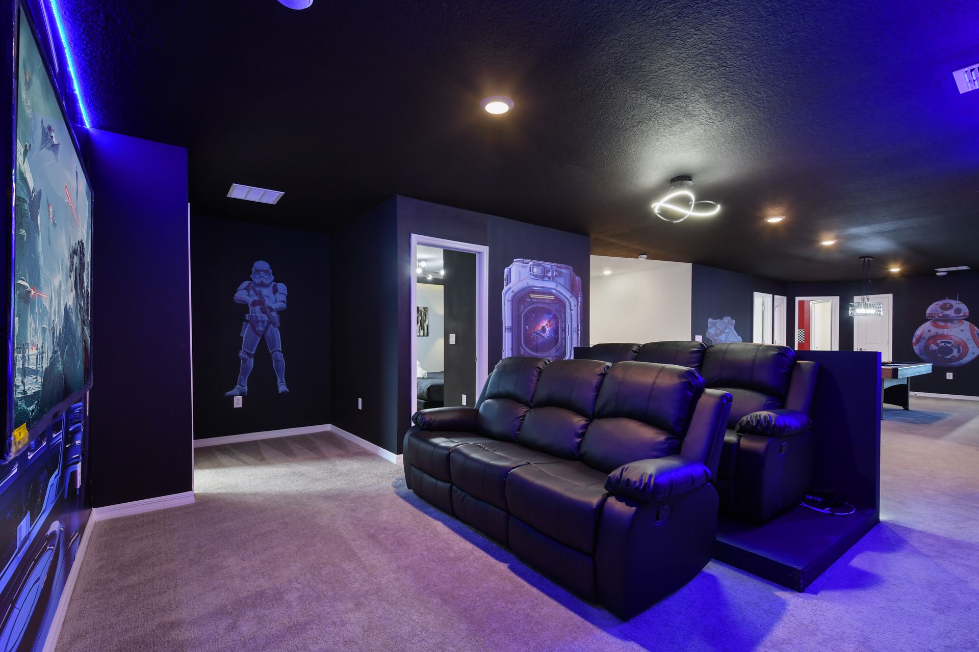 Epic galaxy-themed theater with tiered recliners, murals, and glowing LED vibes.
