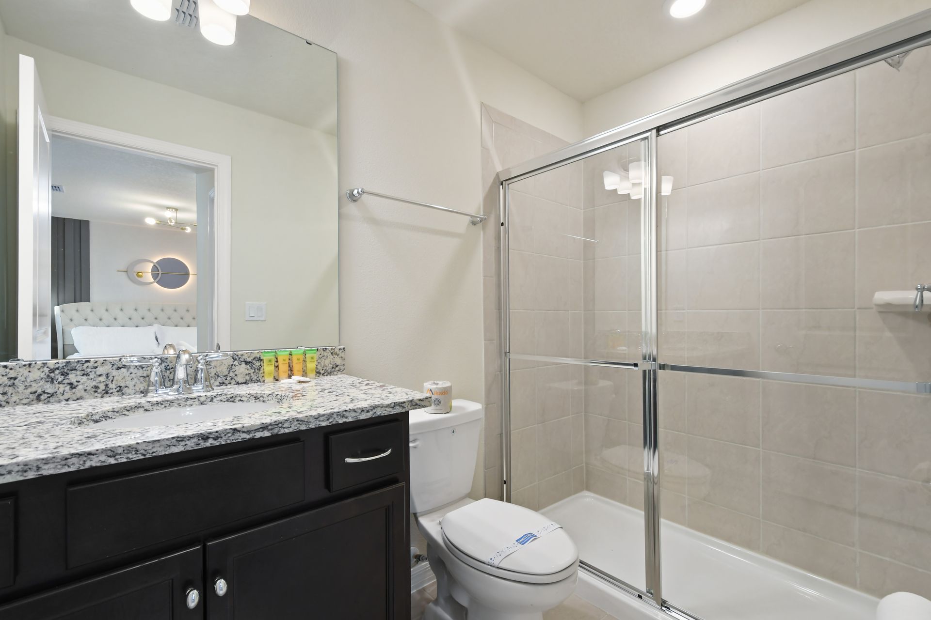 Elegant bathroom with glass shower, granite vanity, and private suite access.
