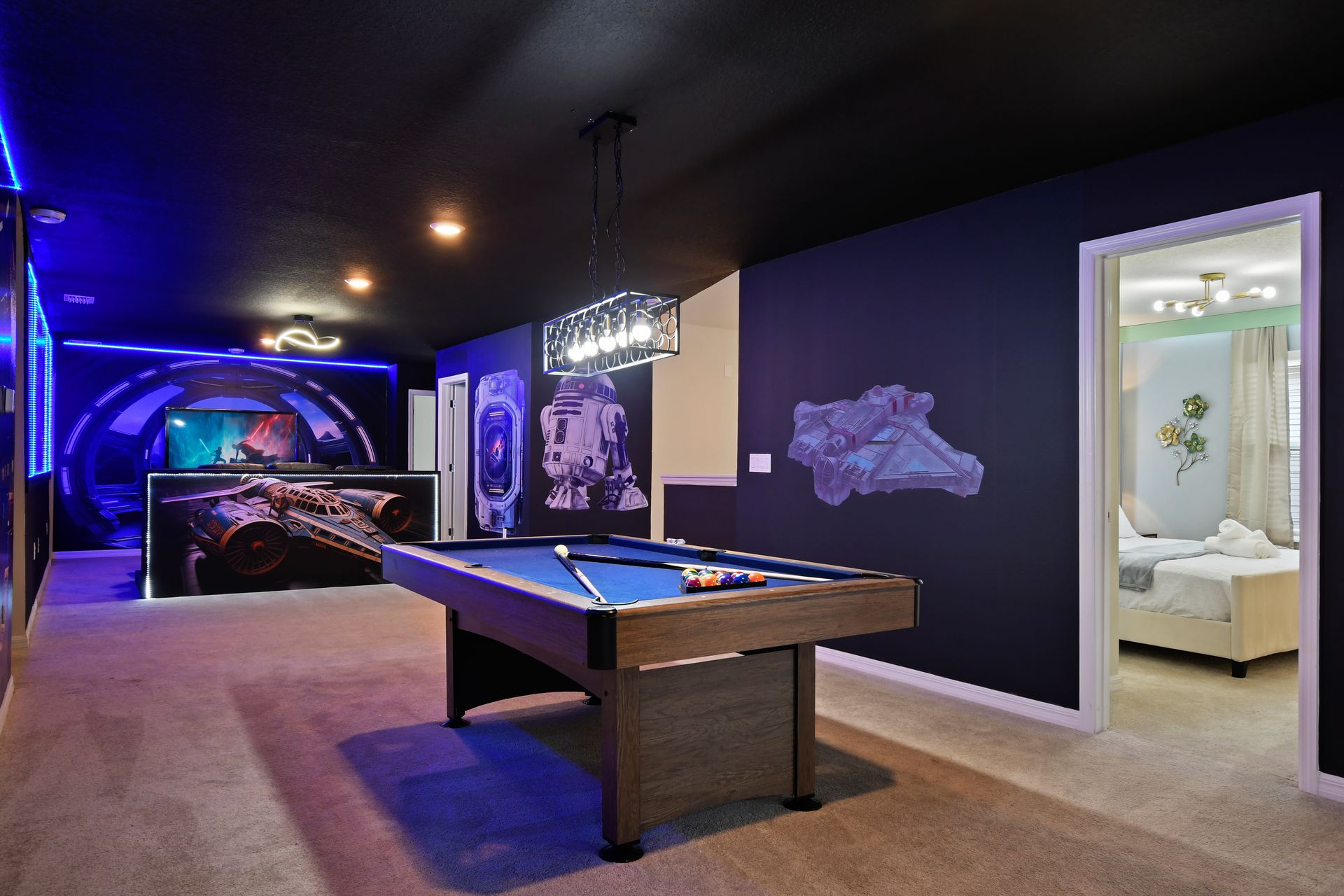 Galaxy-themed game loft with pool table, LED-lit theater, and space wall art.
