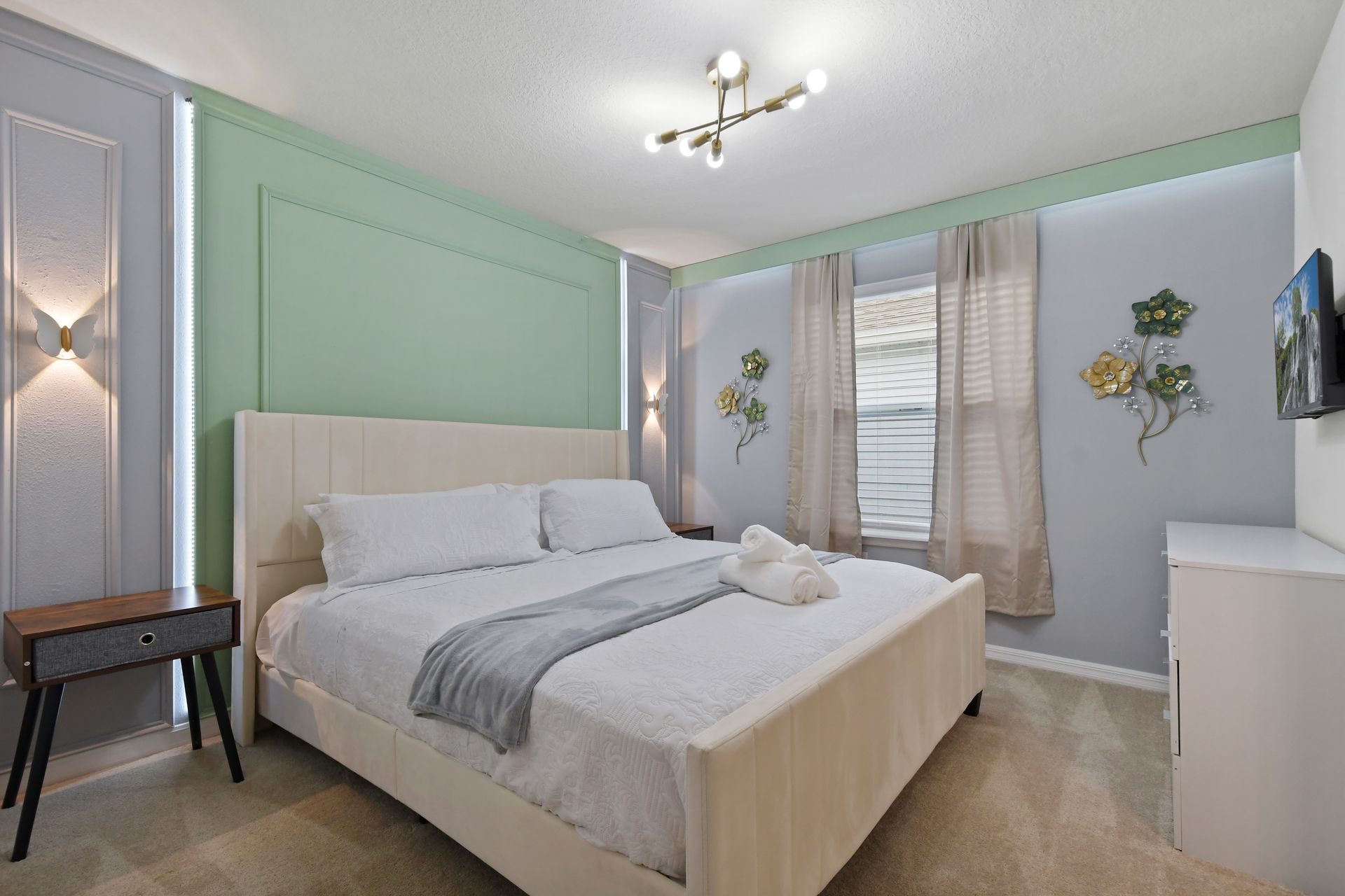 Tranquil king bedroom with pastel tones, floral accents, and soft natural light.

