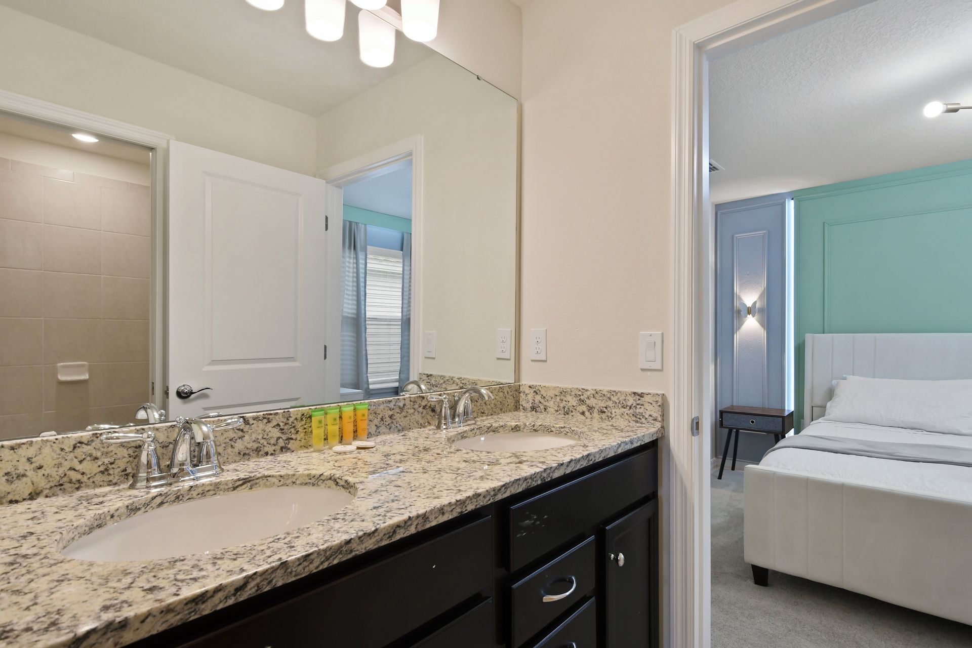 Modern double vanity bathroom with granite counters and direct bedroom access.
