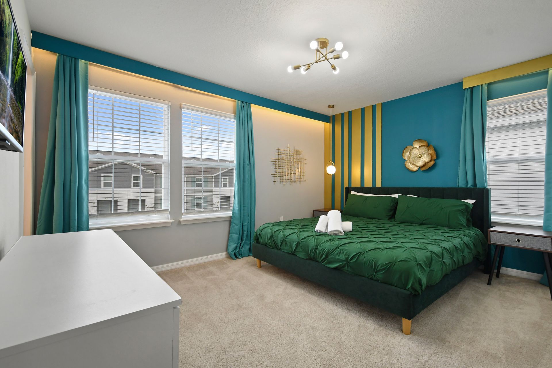 Vibrant king bedroom with emerald tones, gold accents, and plenty of natural light.
