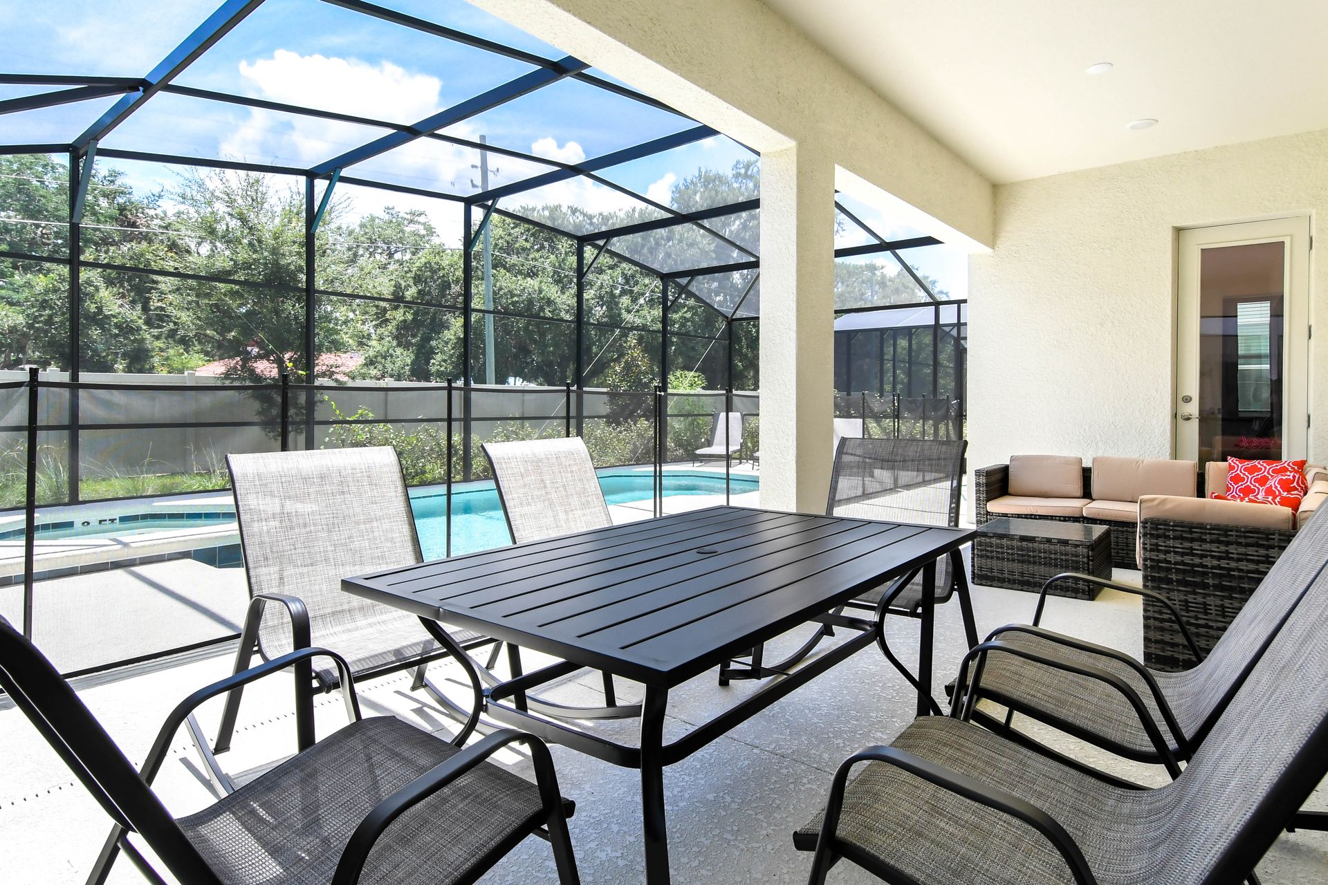 Screened-in patio with outdoor dining, cozy seating, and a private pool for relaxation.