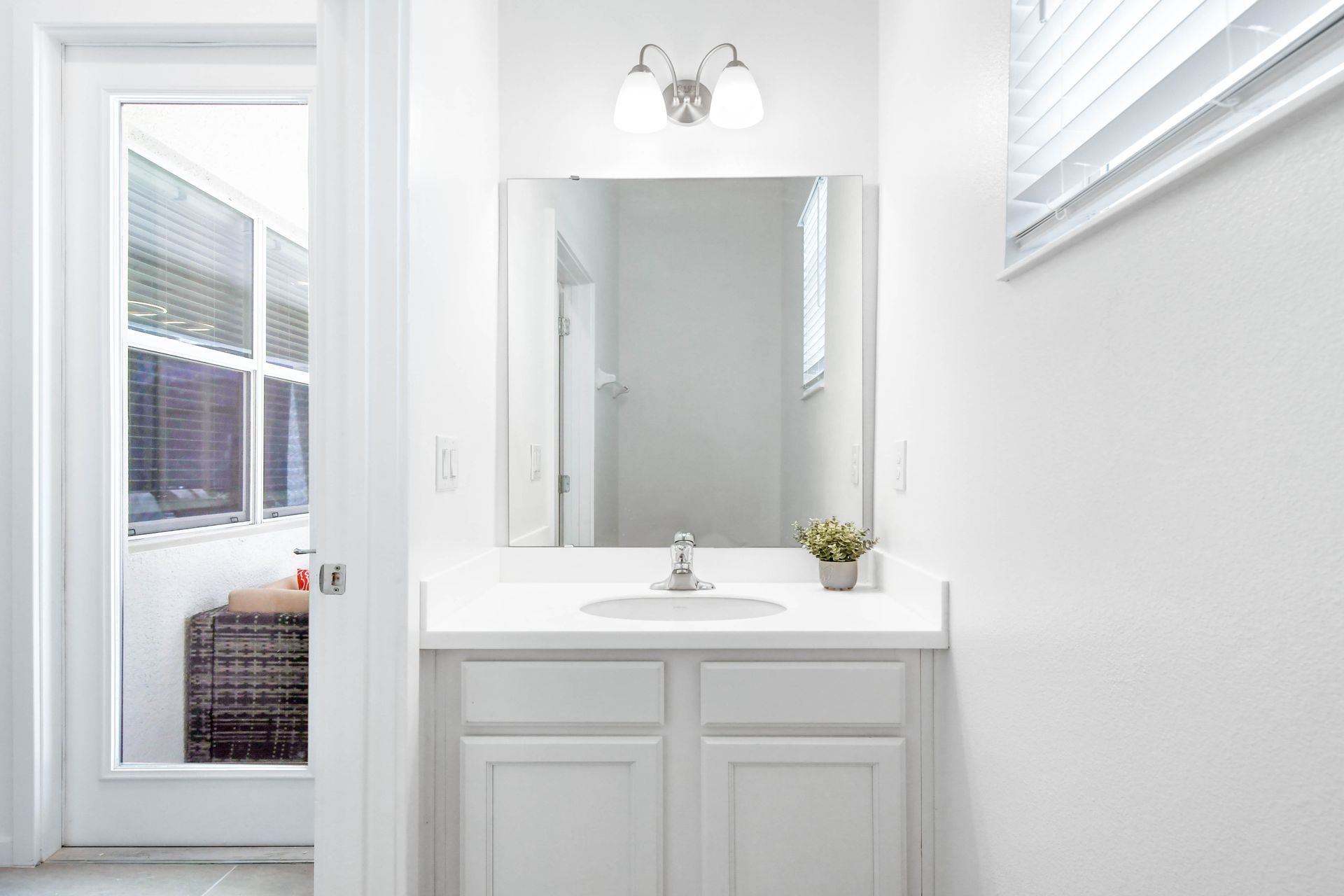 Bright and modern vanity area with sleek white finishes and direct patio access.