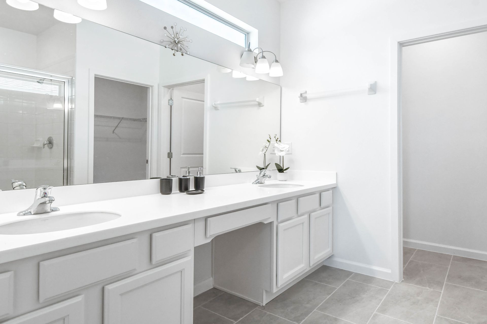 Spacious modern bathroom with dual sinks, a large mirror, and a sleek walk-in shower.