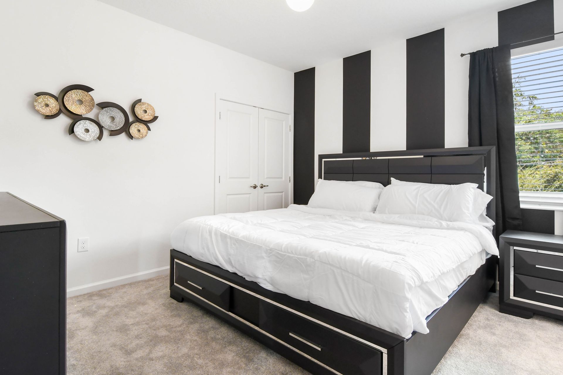 Modern black-and-white bedroom with a plush king bed, bold décor, and a smart TV.