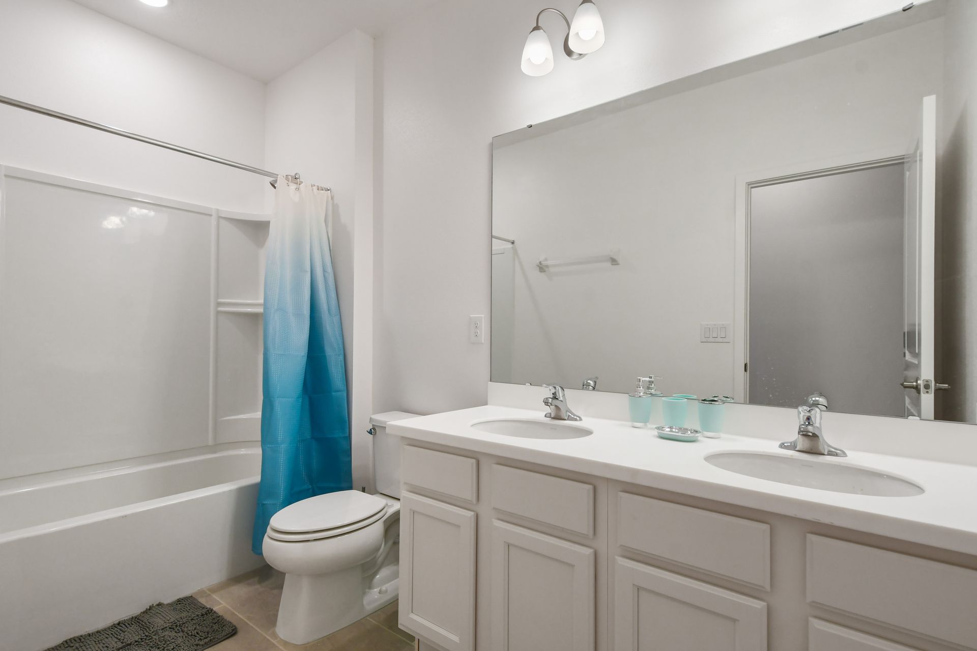 Bright and clean bathroom with double sinks and a refreshing ombré shower curtain.