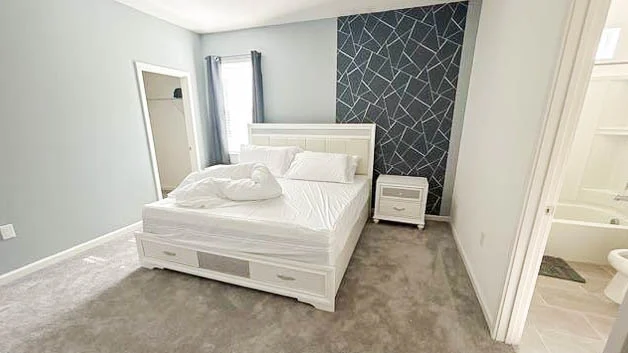Spacious modern bedroom with a king bed, stylish accent wall, and private bathroom.